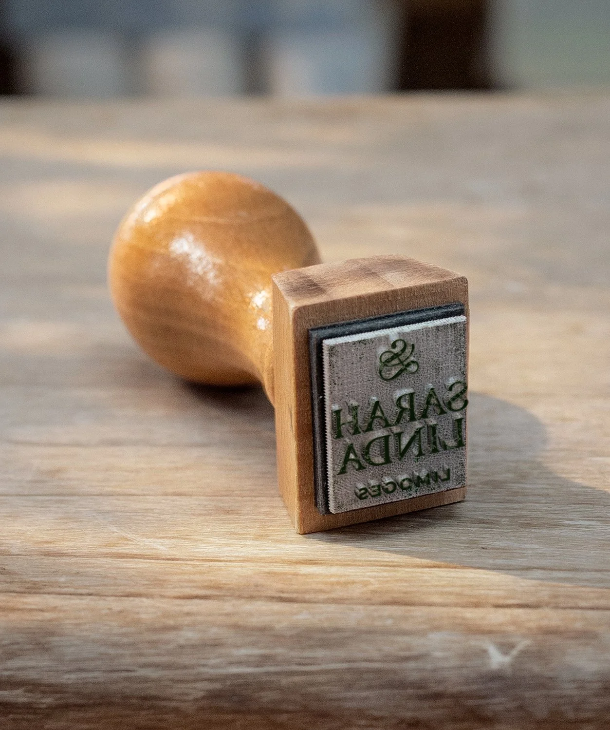 Wooden rubber stamp reading “SARAH LINDA” beside a wooden handle, sensual tableware, branding, web design and editorial project by Automne Studio.