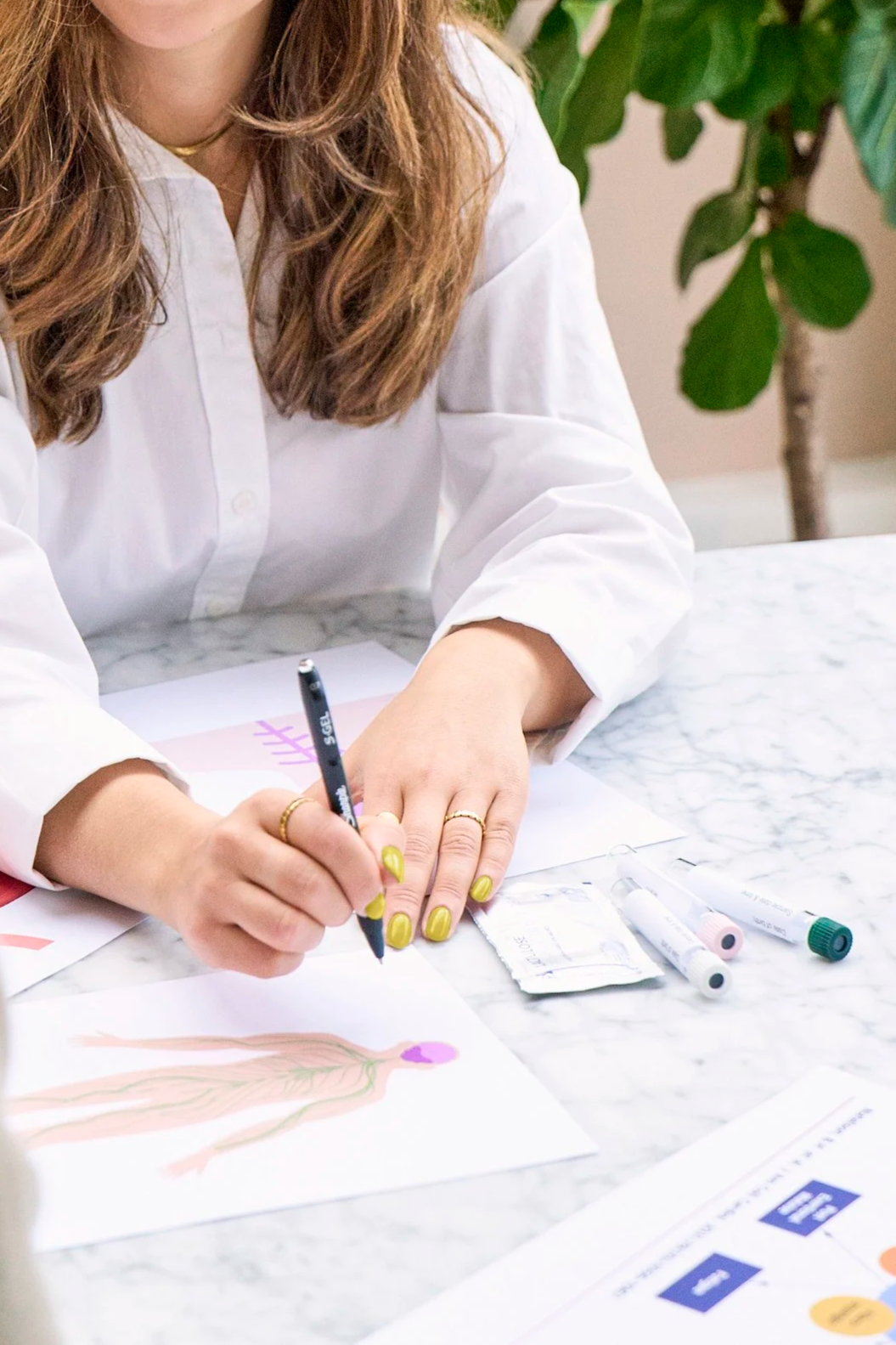 A woman with green painted nails holding a pen and explaining how the nervous system works..