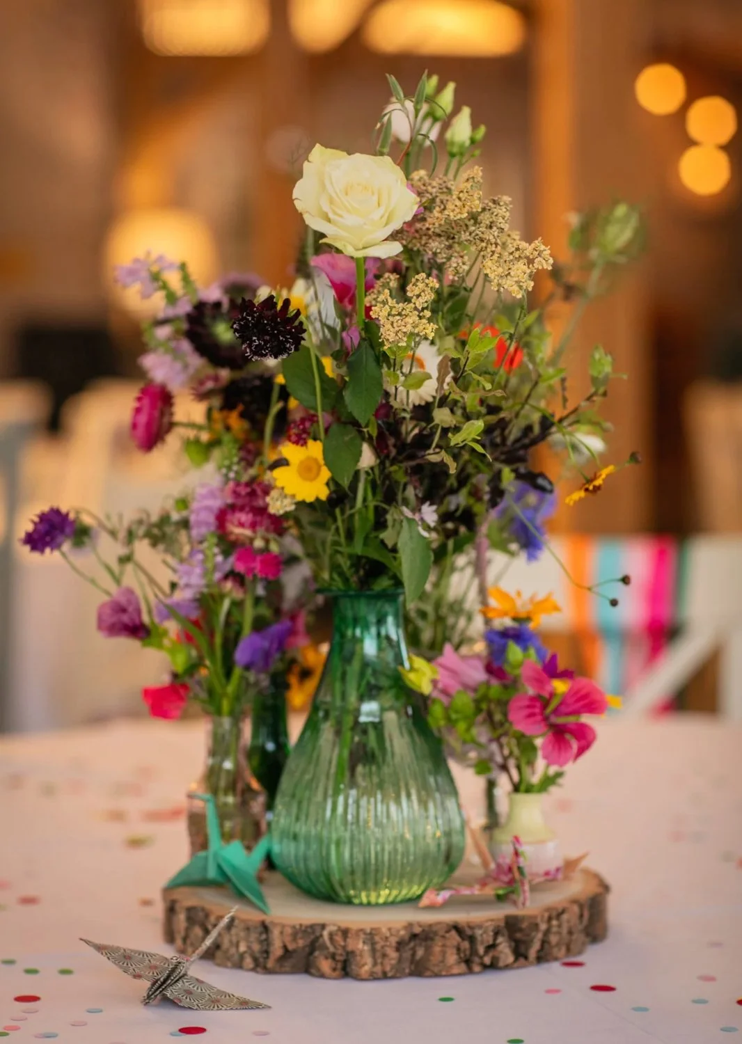 Colorful wildflower bouquet in green glass vases on a wooden slab table
