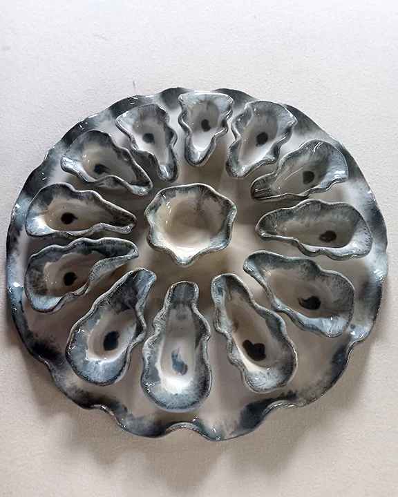 Decorative metal dish with flower-shaped indentations arranged in circle.