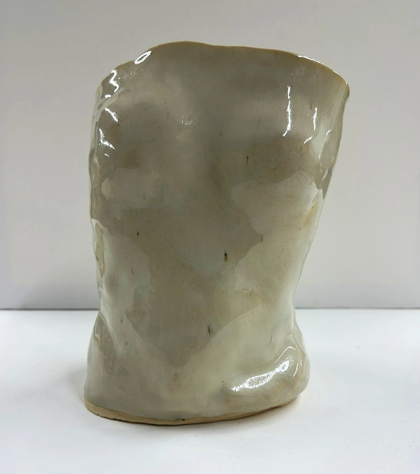 Lizette Terral Pottery Artist A light-colored ceramic mug with uneven, textured surface and irregular shape.