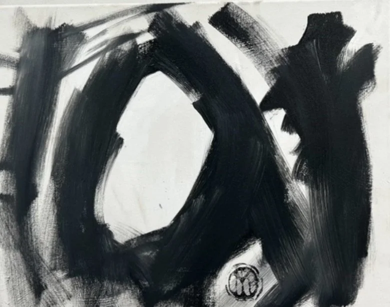 Abstract black brushstrokes on white paper with a small circular symbol at the bottom.