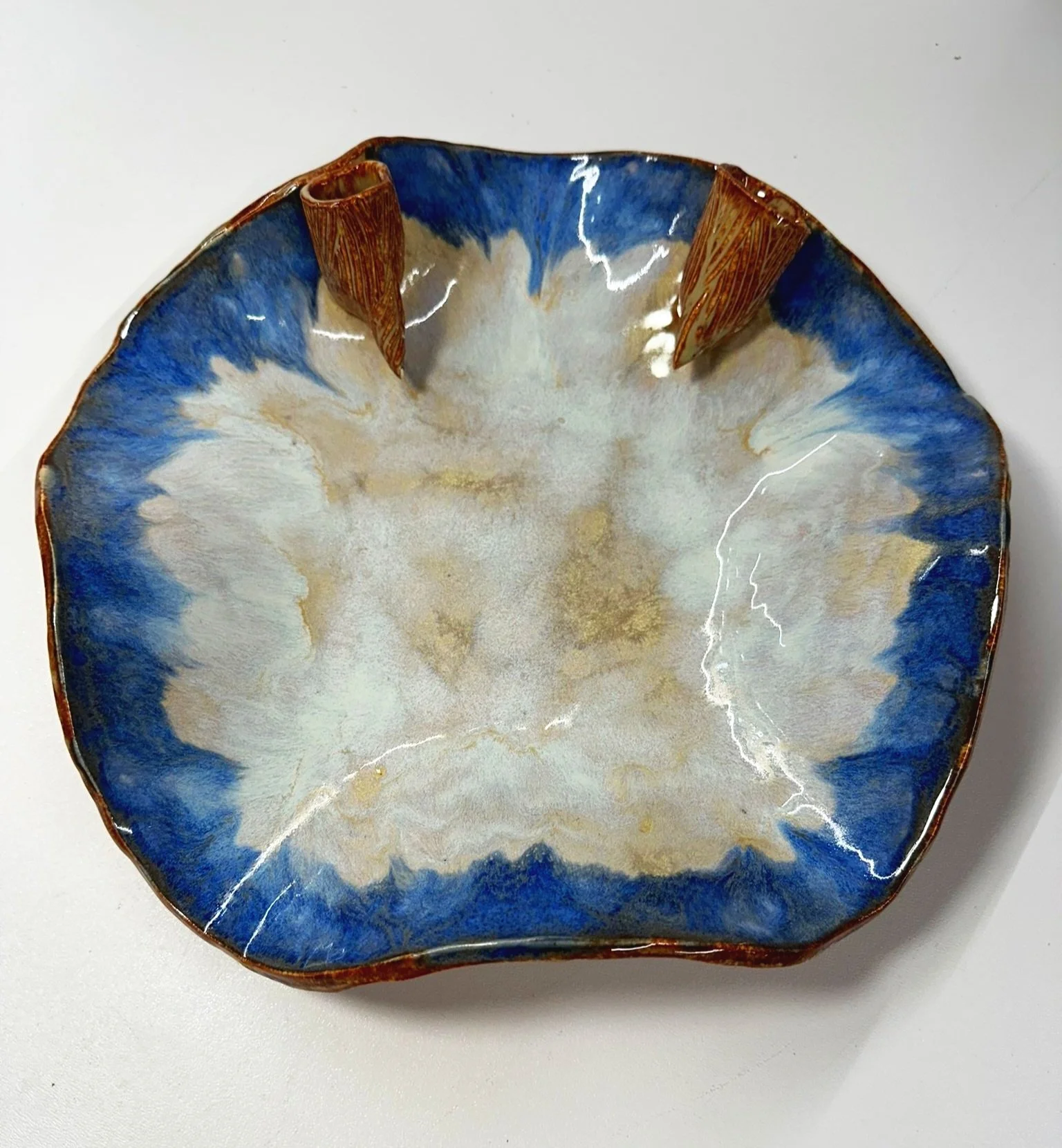 Lizette Terral Pottery Artist A decorative ceramic bowl with a blue, beige, and white glaze design, featuring textured brown accents on the rim.