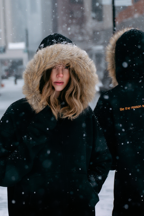 Frau in Winterjacke mit Fellkapuze in Schneelandschaft