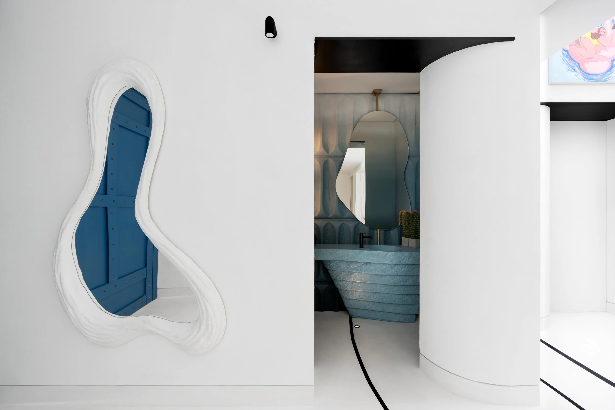 Modern interior with abstract cutout mirror, a blue textured sink, a decorative mirror, and cactus plants.