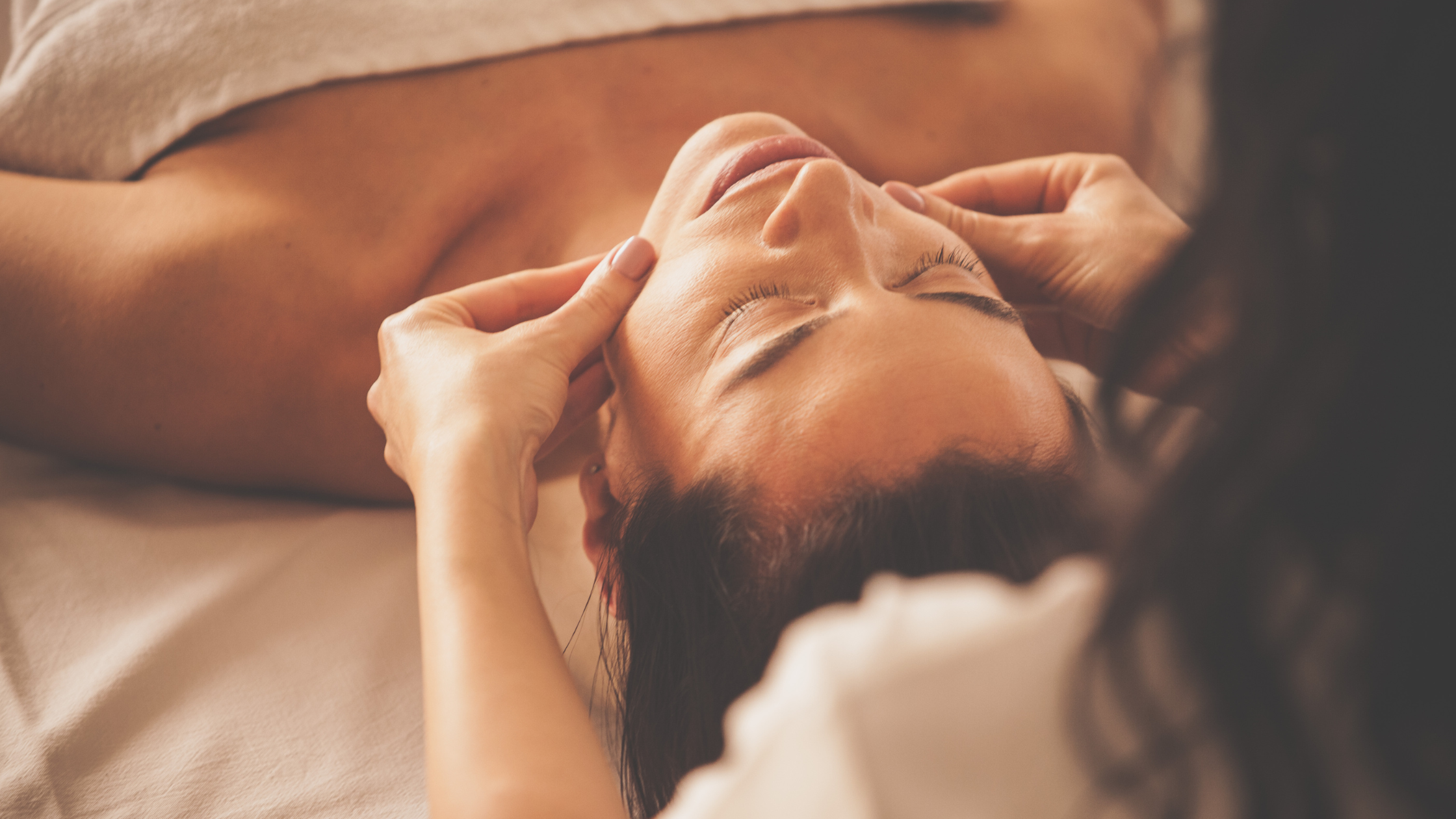 Person receiving a facial massage in a spa setting.