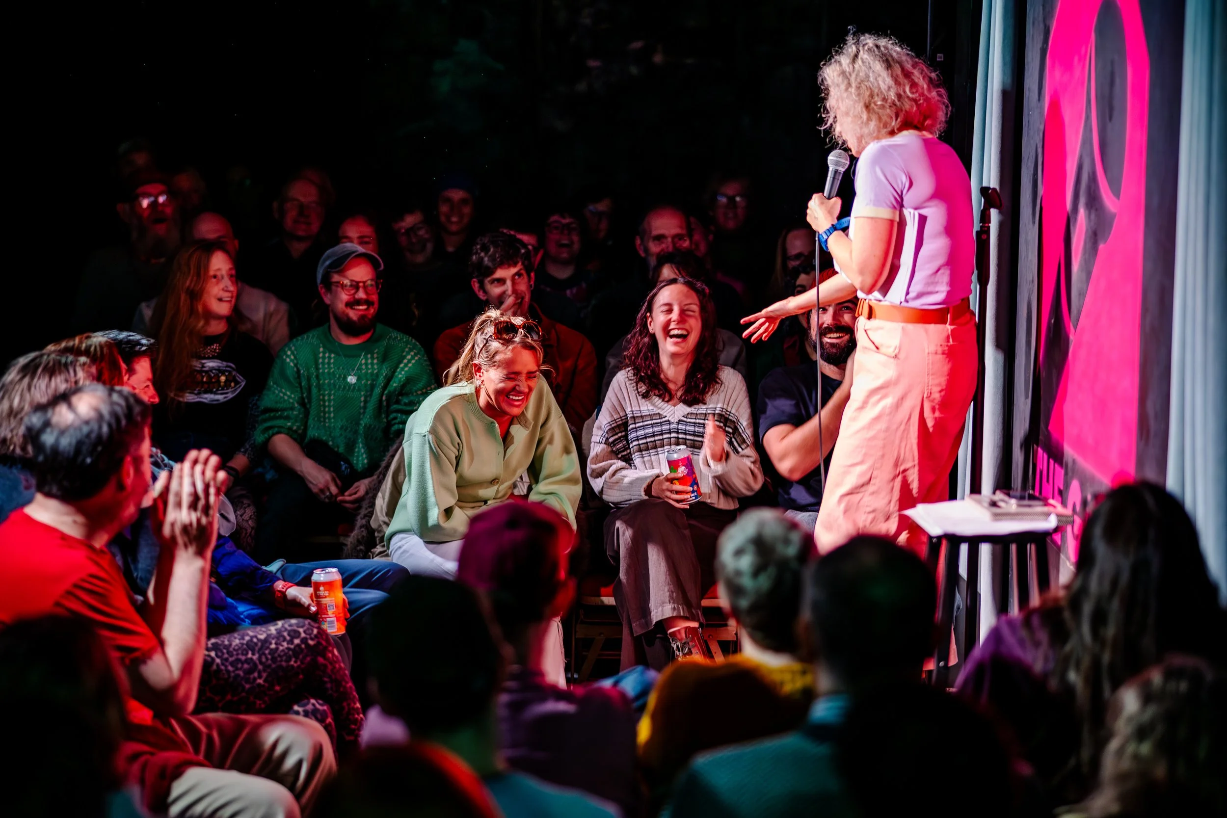 Comedian Felicity Ward performing onstage in front of a smiling audience at The Gaffe Comedy Club
