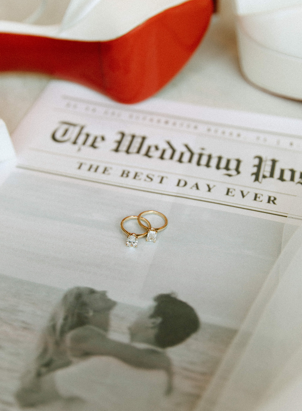 Wedding rings with a diamond, wedding invitation with the text 'The Wedding Pur.', a red and white flower, and a black and white photo of a couple kissing.