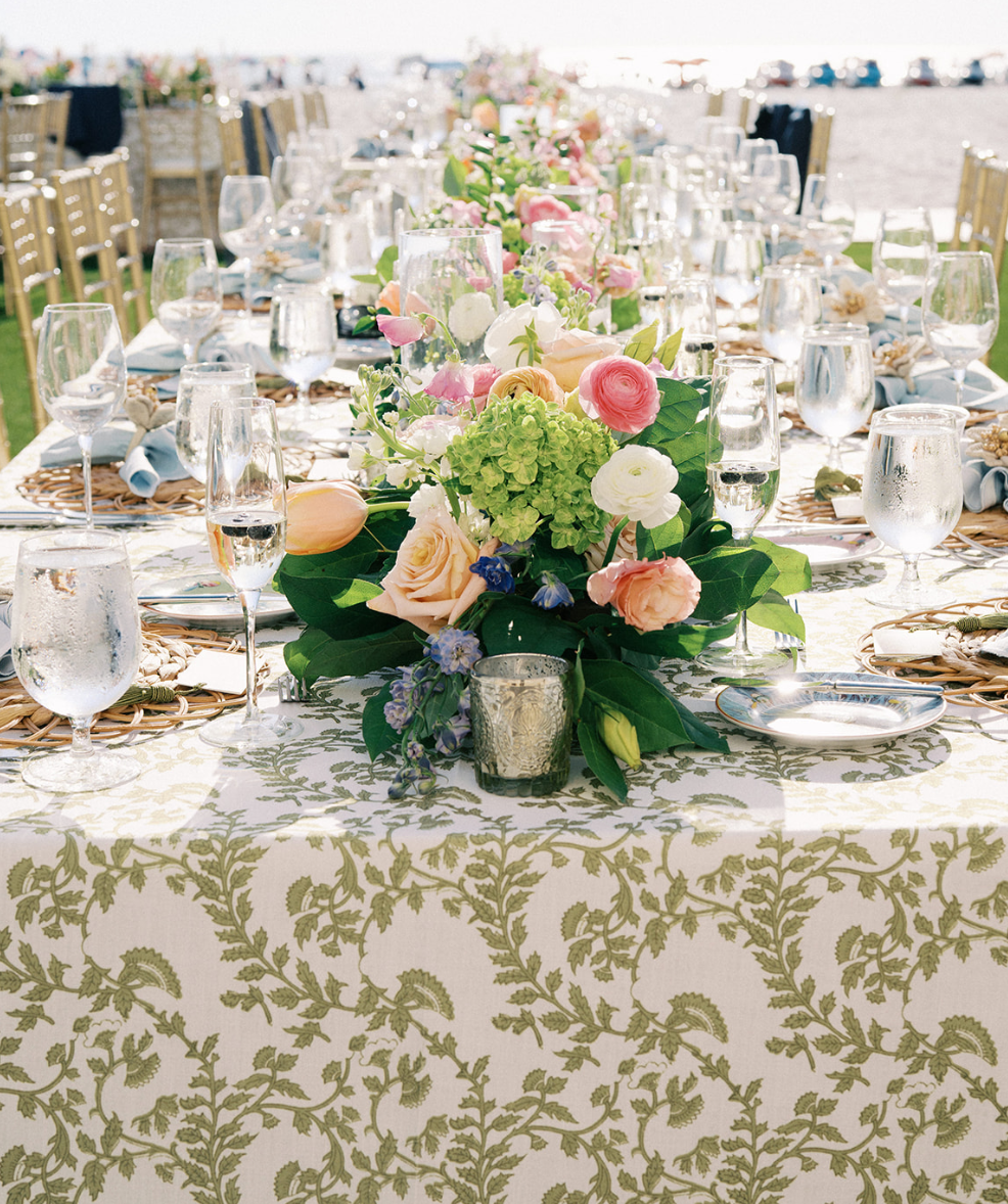 Elegant outdoor wedding reception table decorated with a floral centerpiece, glassware, and tableware.