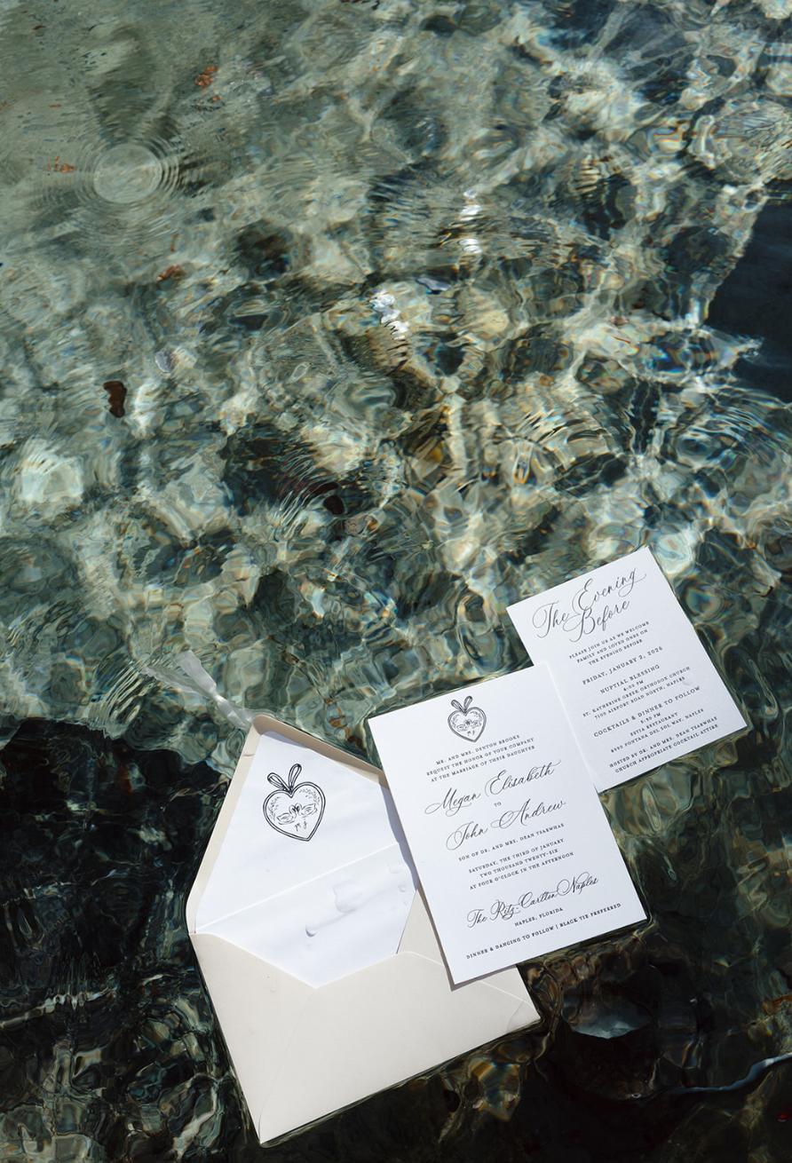 Wedding invitation cards and an envelope floating in clear water.