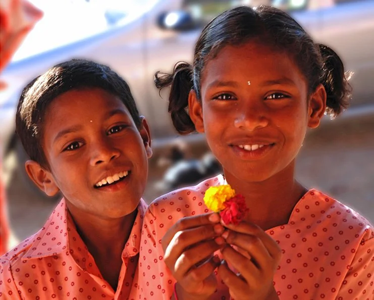 En glad pojke och en glad flicka hållandes några blommor