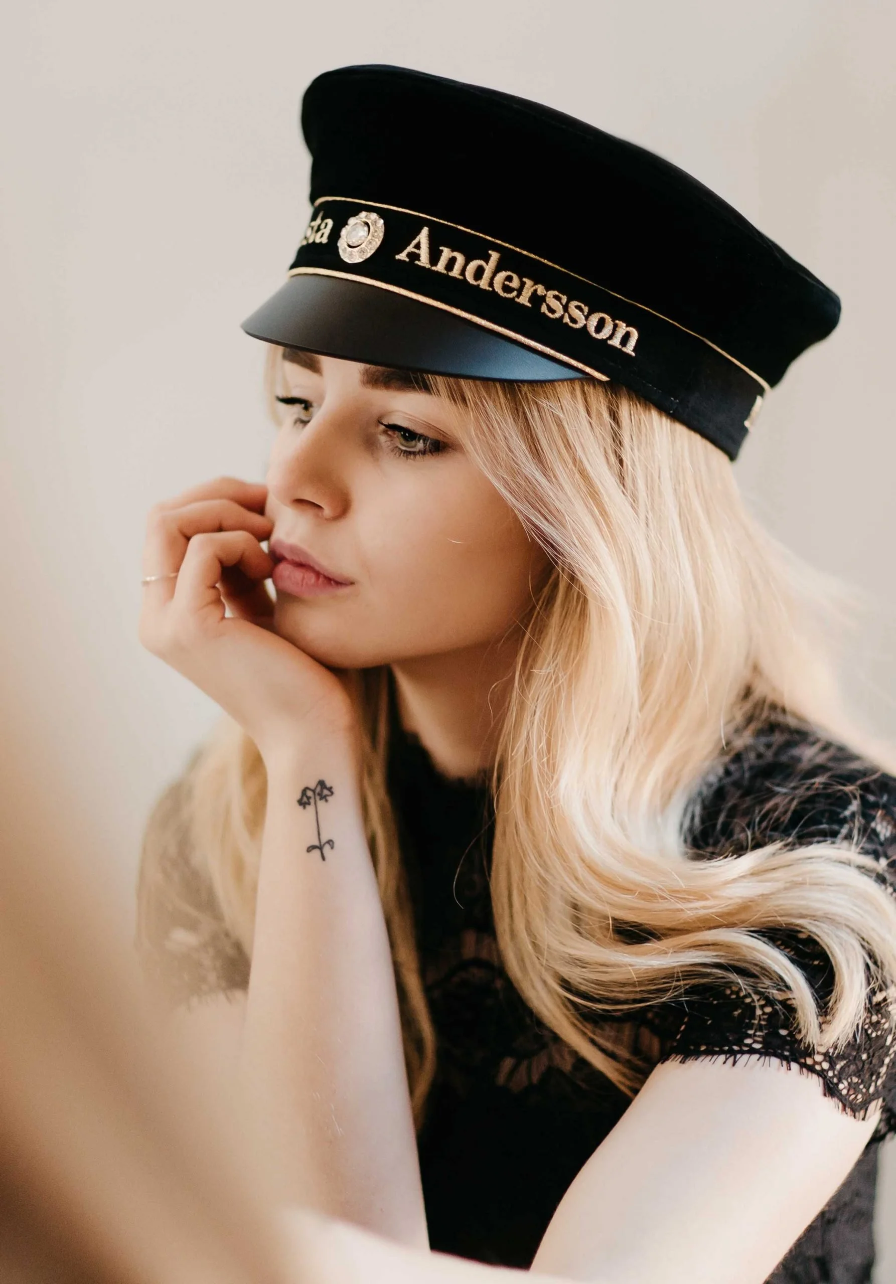 Ung kvinna med studentmössa, blickar bortåt, med en blomtatuering på handleden.
