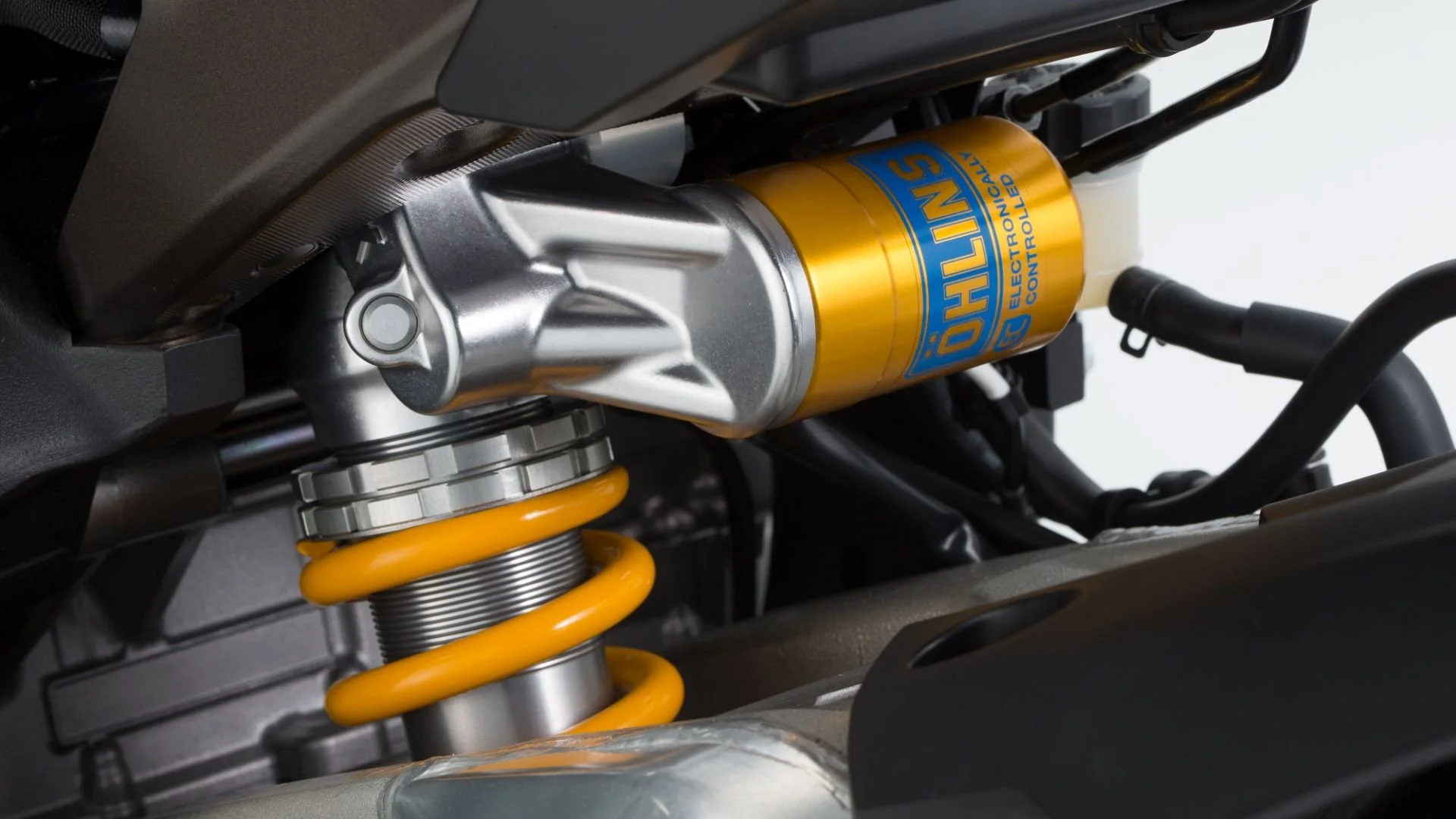 Närbild av en gul och grå fjäderstötdämpare från Öhlins, monterad på en motorcykel.