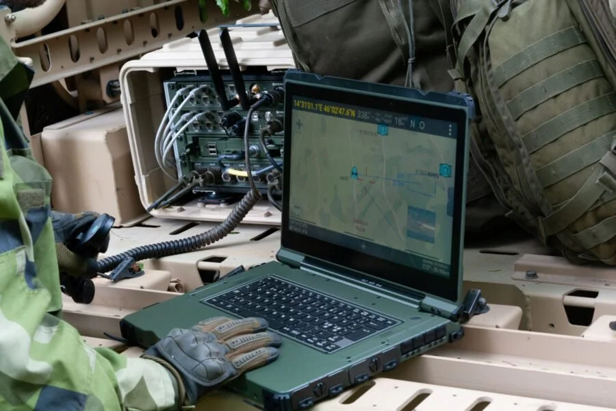 Militär personal använder en bärbar dator och kommunikationsutrustning i ett fordon.