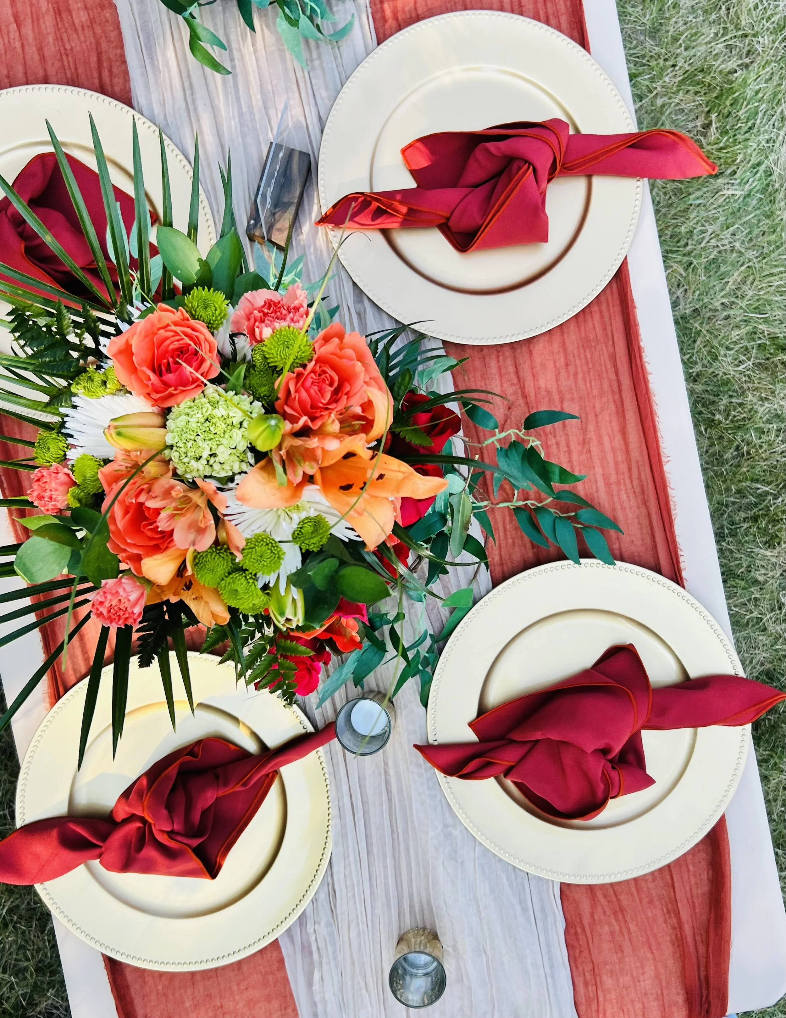 Table setting with elegant floral arrangement and red napkins on plates.