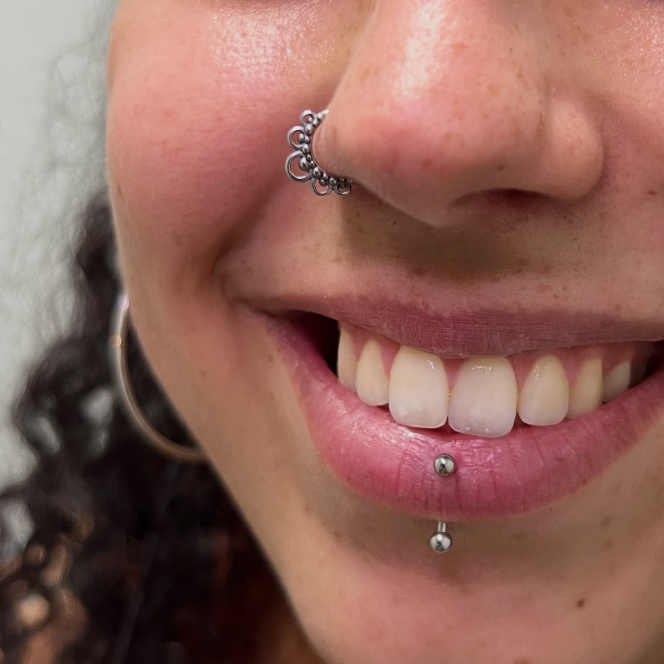 Hay combinaciones que simplemente funcionan 🖤

Este nostril con aro ornamental es una pieza bastante protagonista, pero encaja perfectamente con el labret vertical y, al fondo, esa argolla de mayor tama&ntilde;o en el l&oacute;bulo. Cada joya aporta