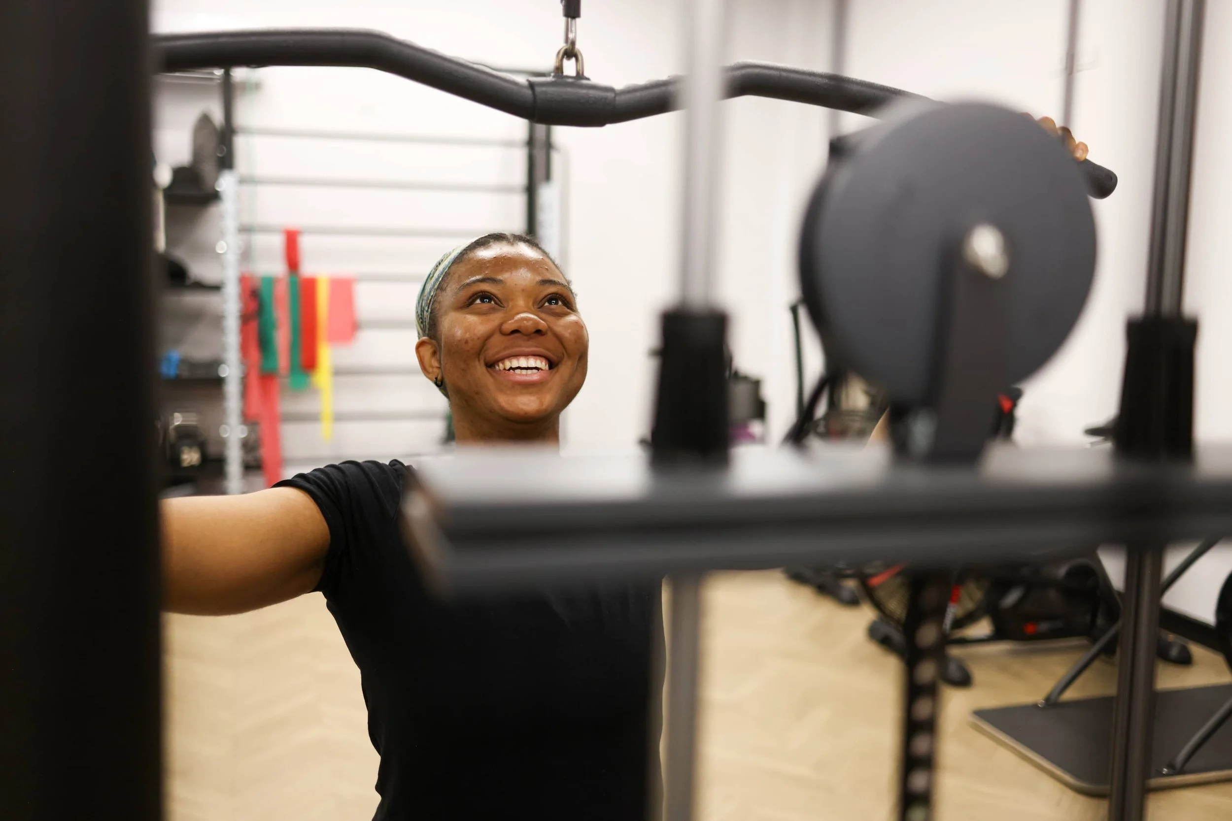 A woman smiling while working out with gym equipment in a fitness studio.