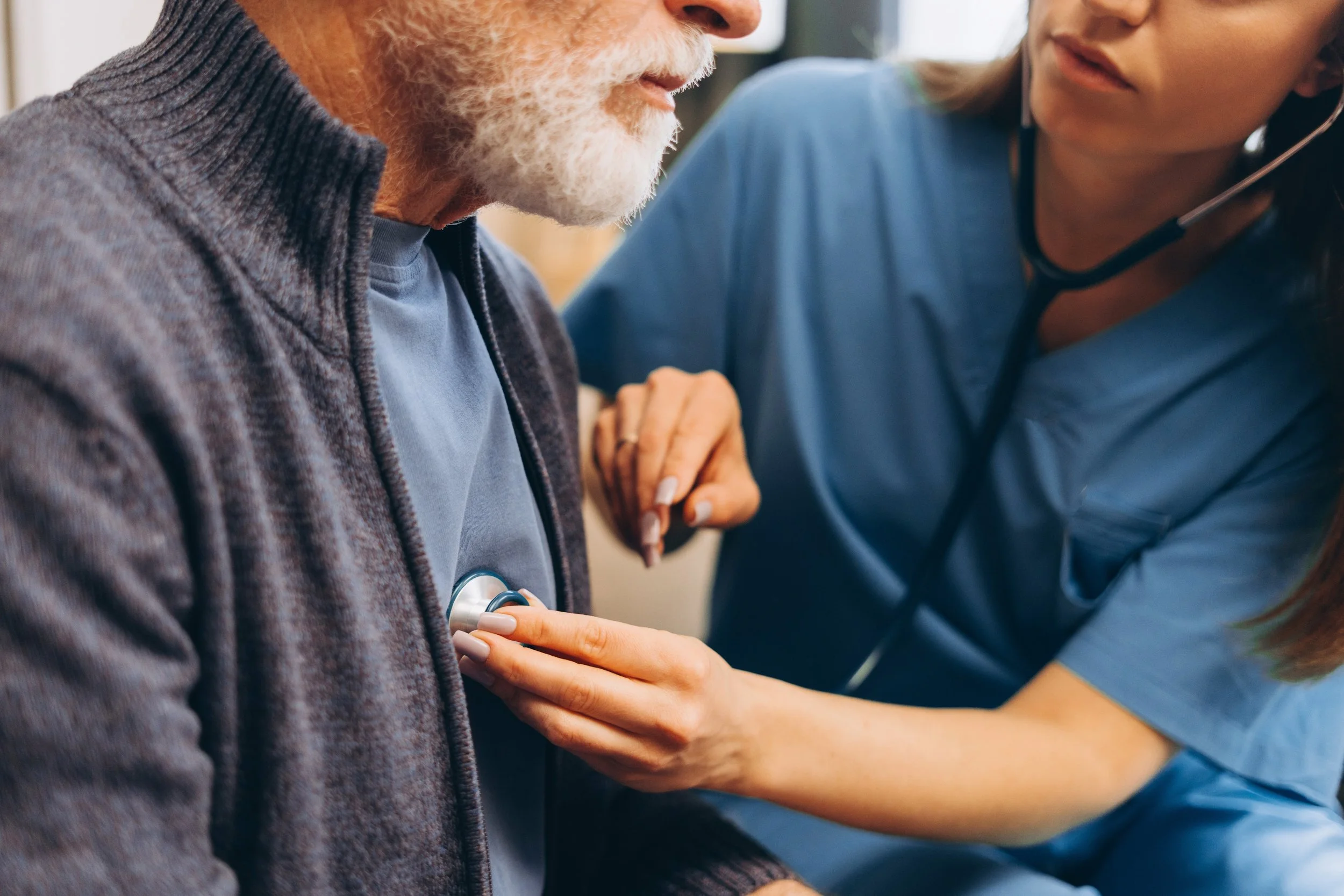Nurse checking an elderly man's heartbeat with a stethoscope.