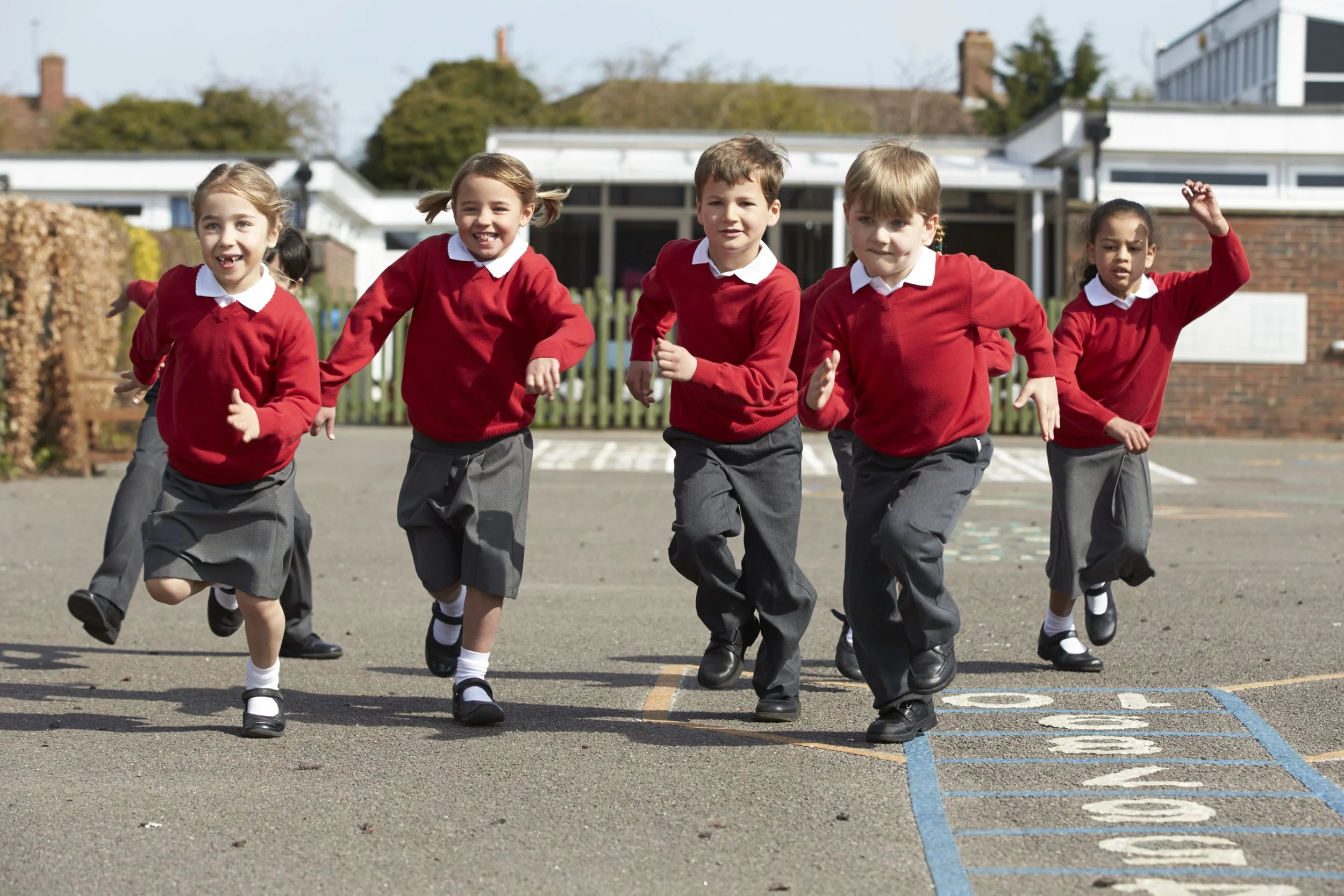 Elementary school children in red sweaters running on playground