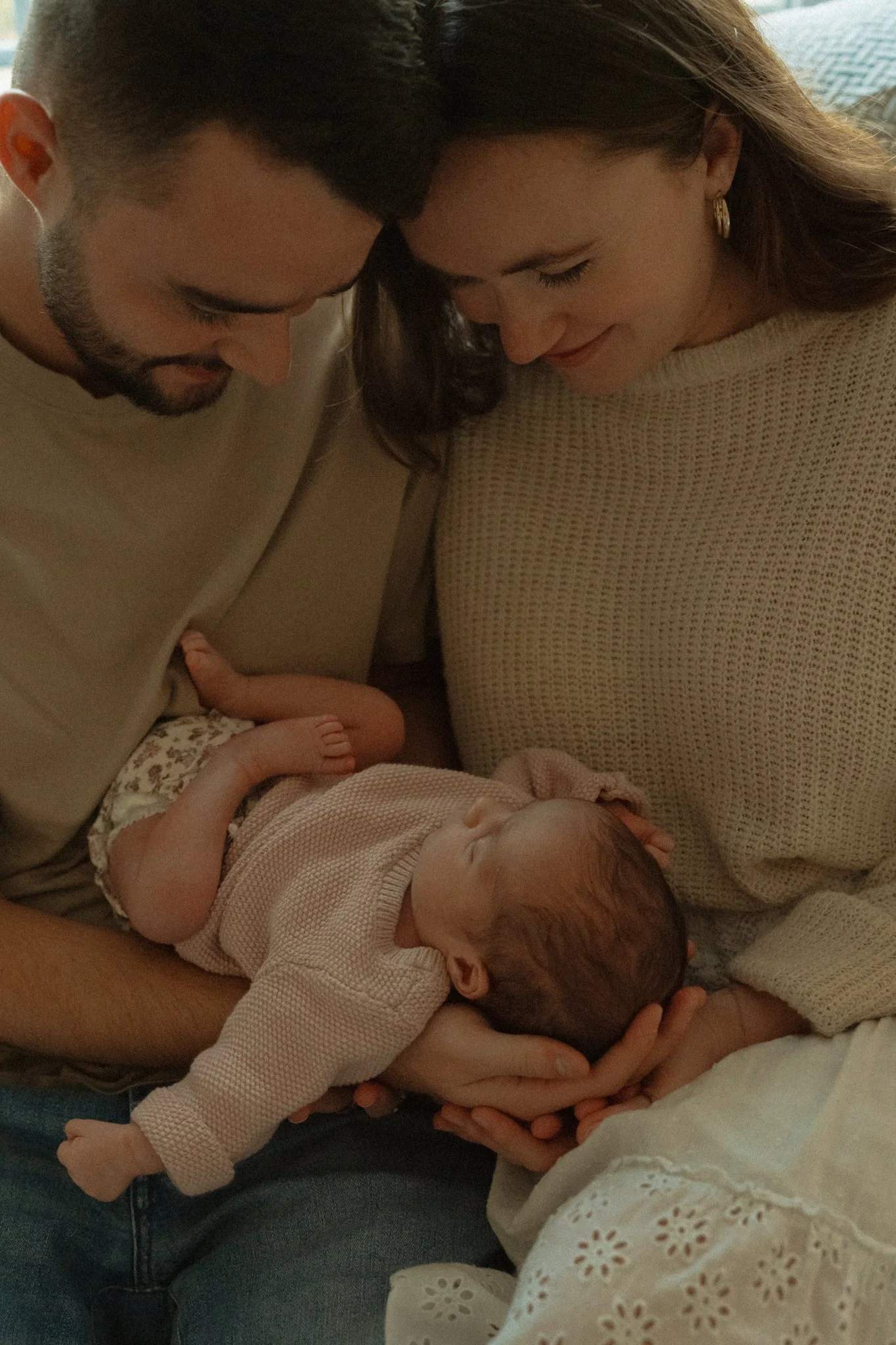 New mom and dad cradling their newborn daughter in their arms
