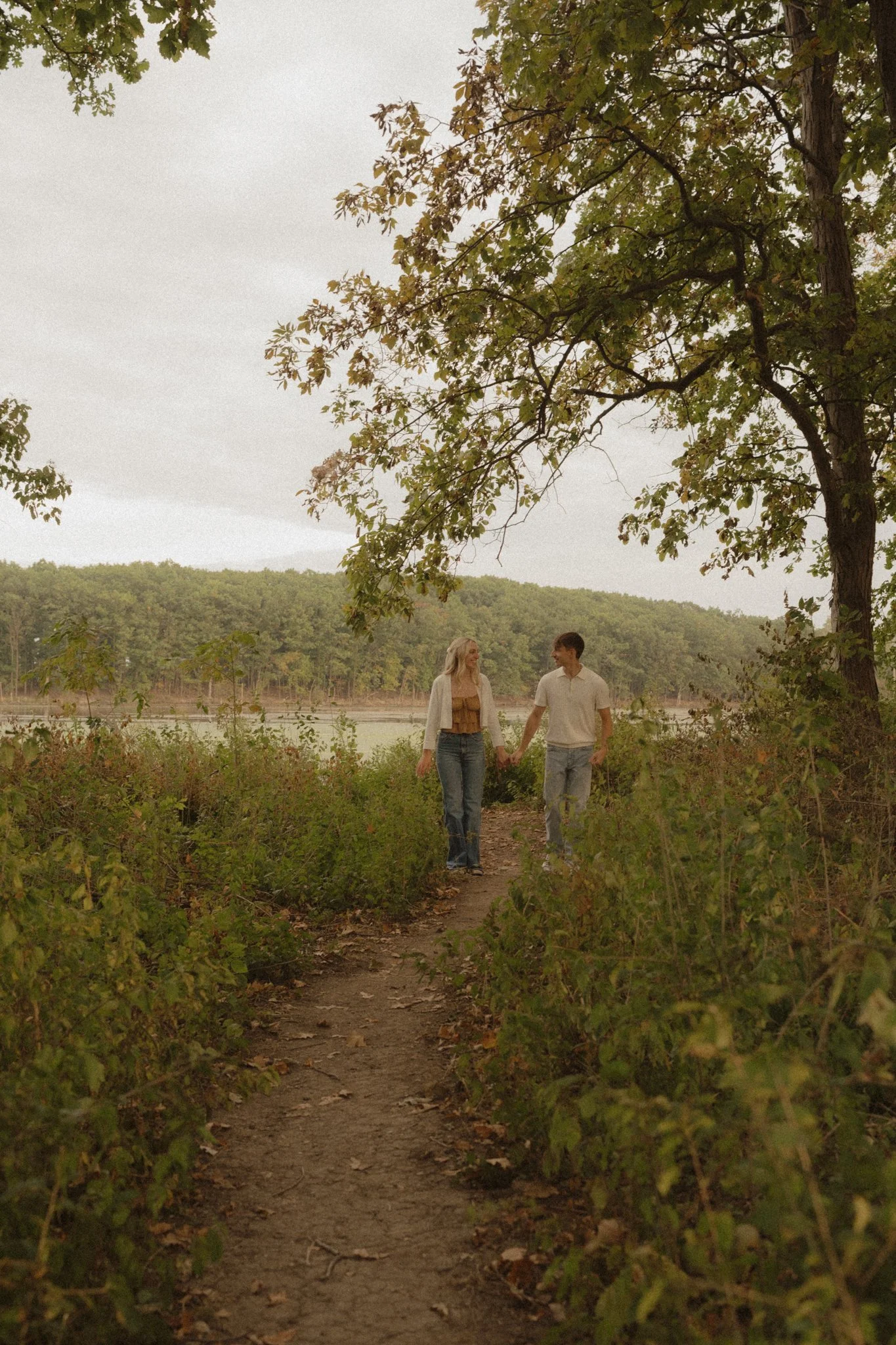 A cute couple walking hand in hand through the forest.