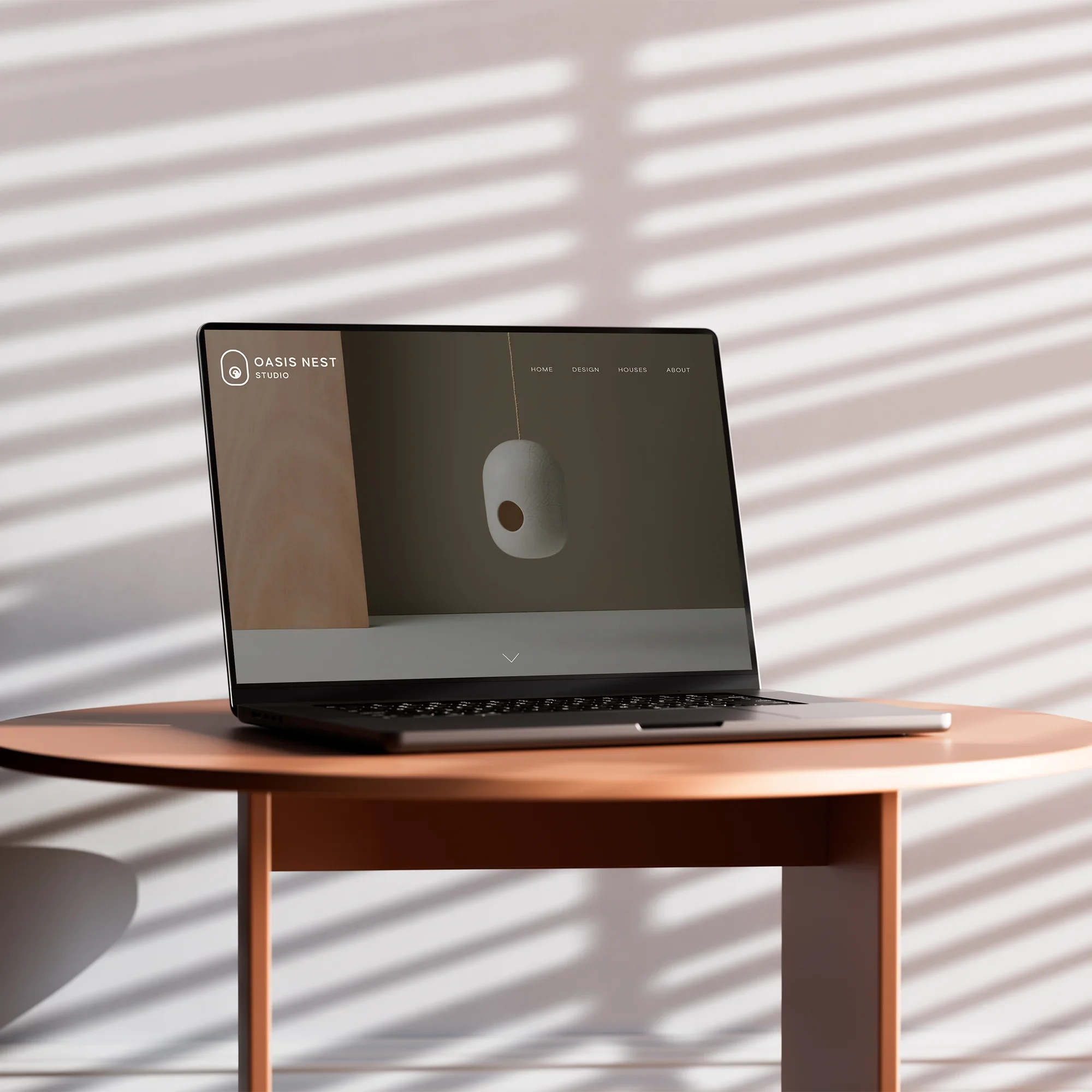 Open laptop on a round wooden table with shadows from window blinds cast on the wall behind it.