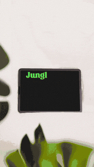 Tablet on a white surface displaying an animated green ‘Jungl’ logo, framed by soft-focus green leaves for a clean, modern studio look.