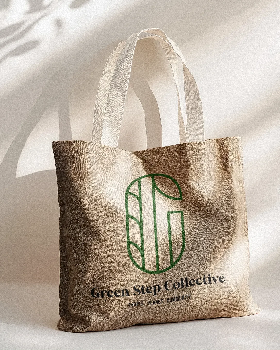 Beige tote bag with green logo and black text that says 'Green Step Collective' and 'People - Planet - Community' on a light background.