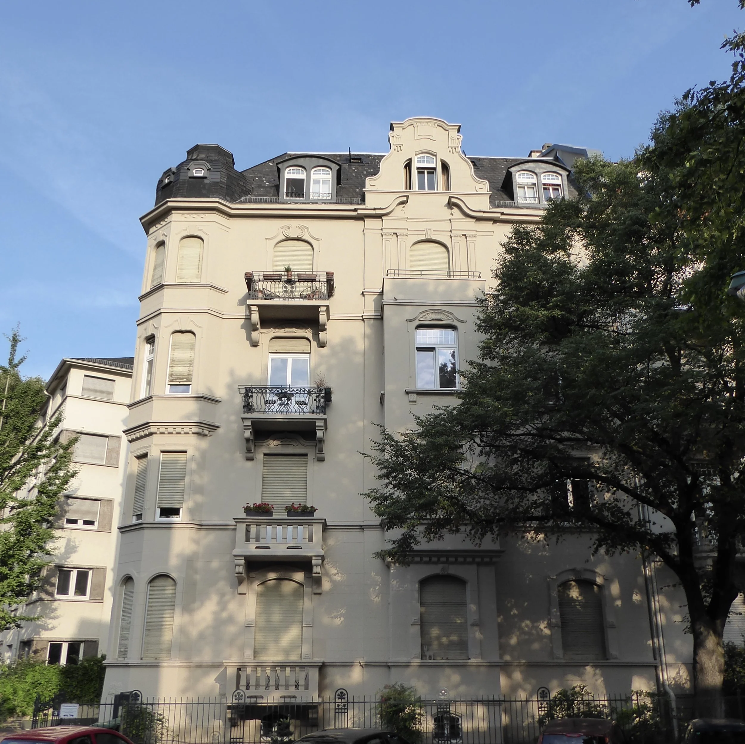 Verzierte Fassade mit großem Baum an der Seite.jpg