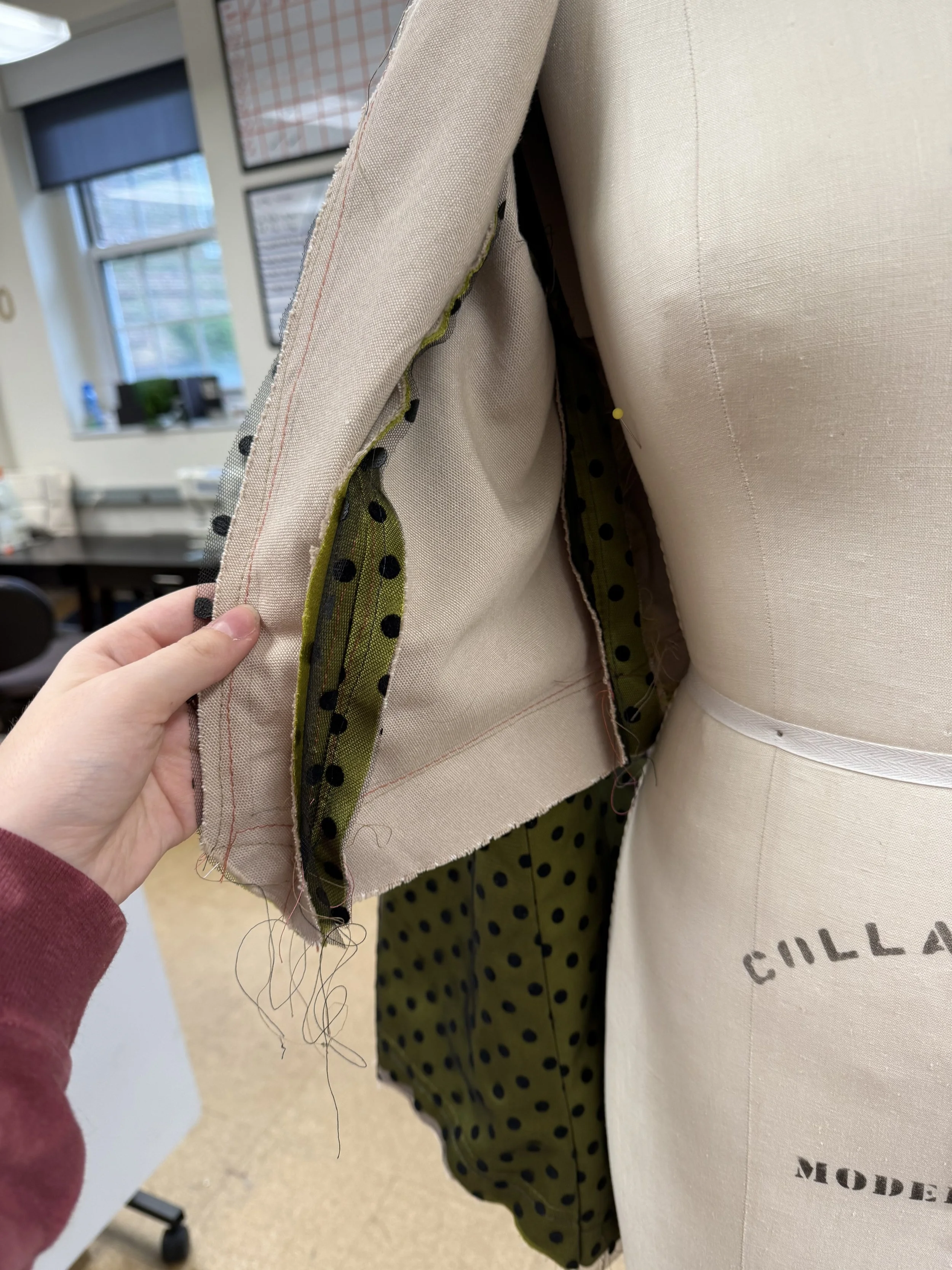 Close-up of a dressmaking mannequin and a sewing pattern, with fabric and lining visible, in a sewing studio.