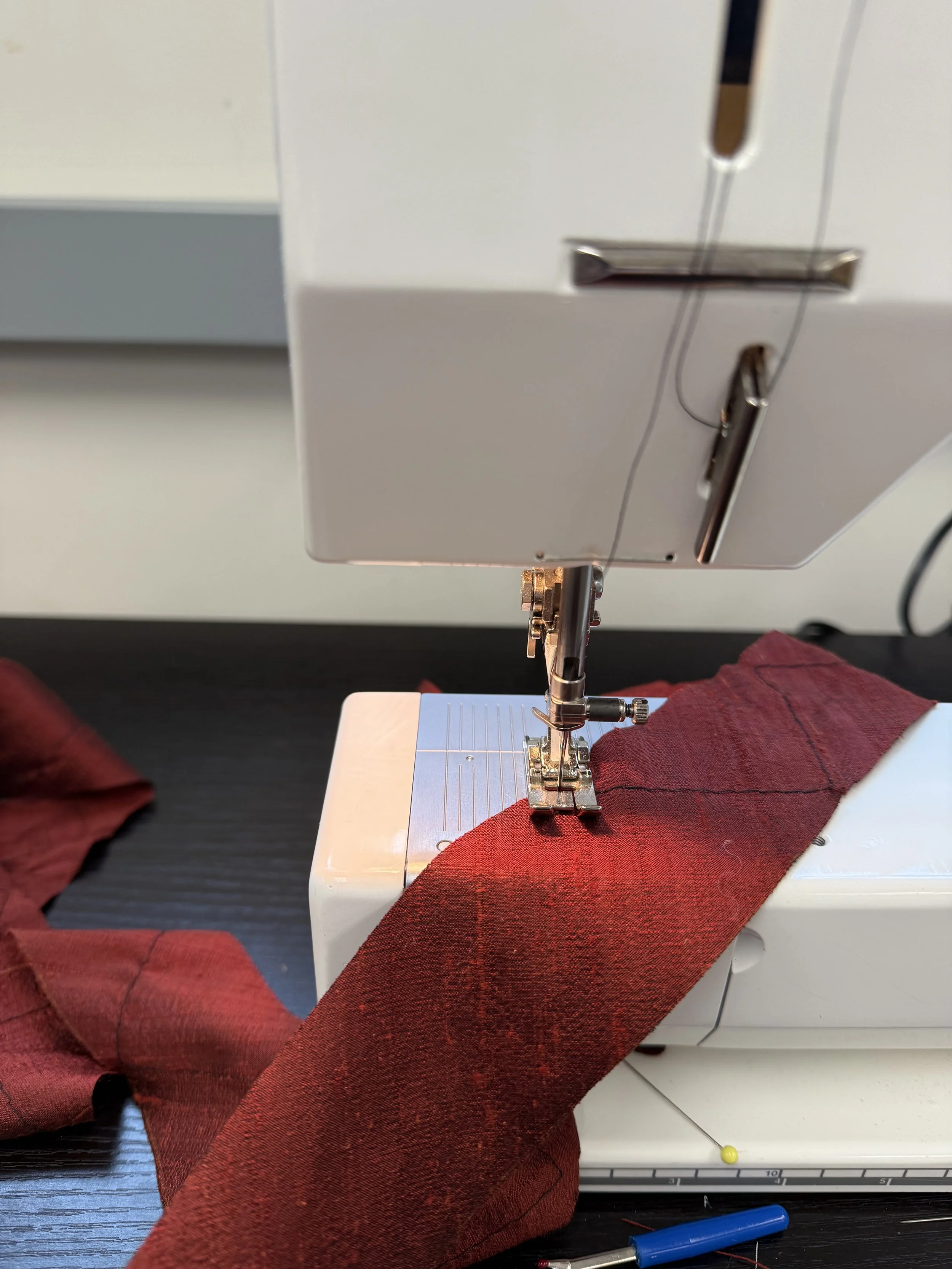 A sewing machine stitching red fabric.