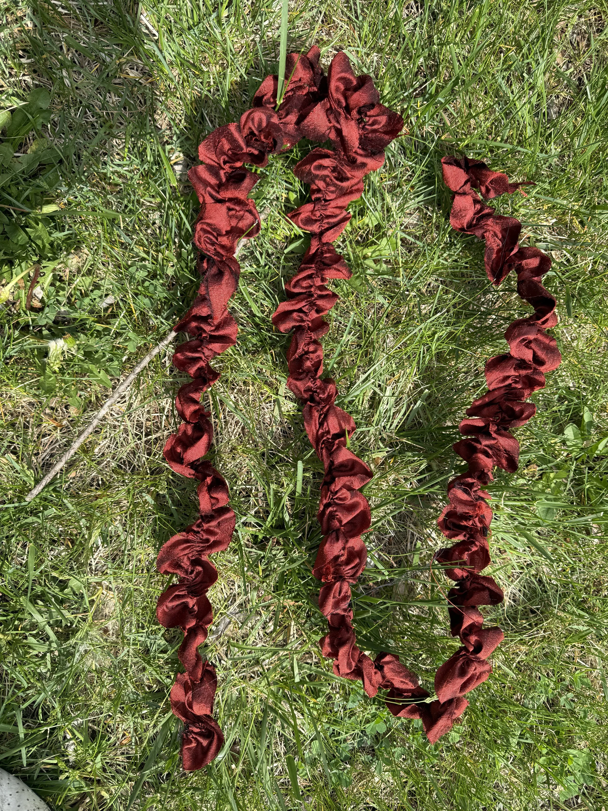 Red fabric with ruffled texture placed on green grass.