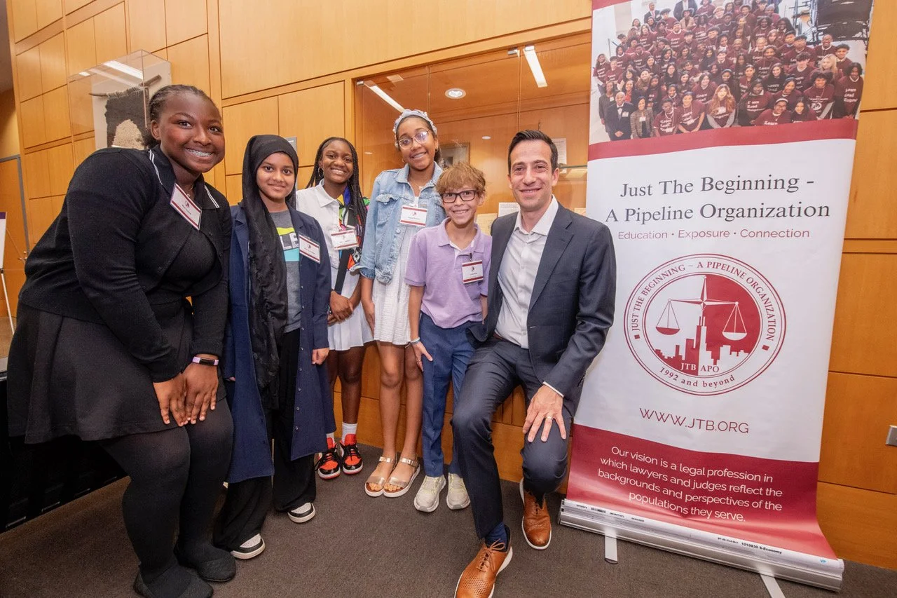 Attorney posing with middle schoolers in front of banner for Just the Beginning - A Pipeline Organization