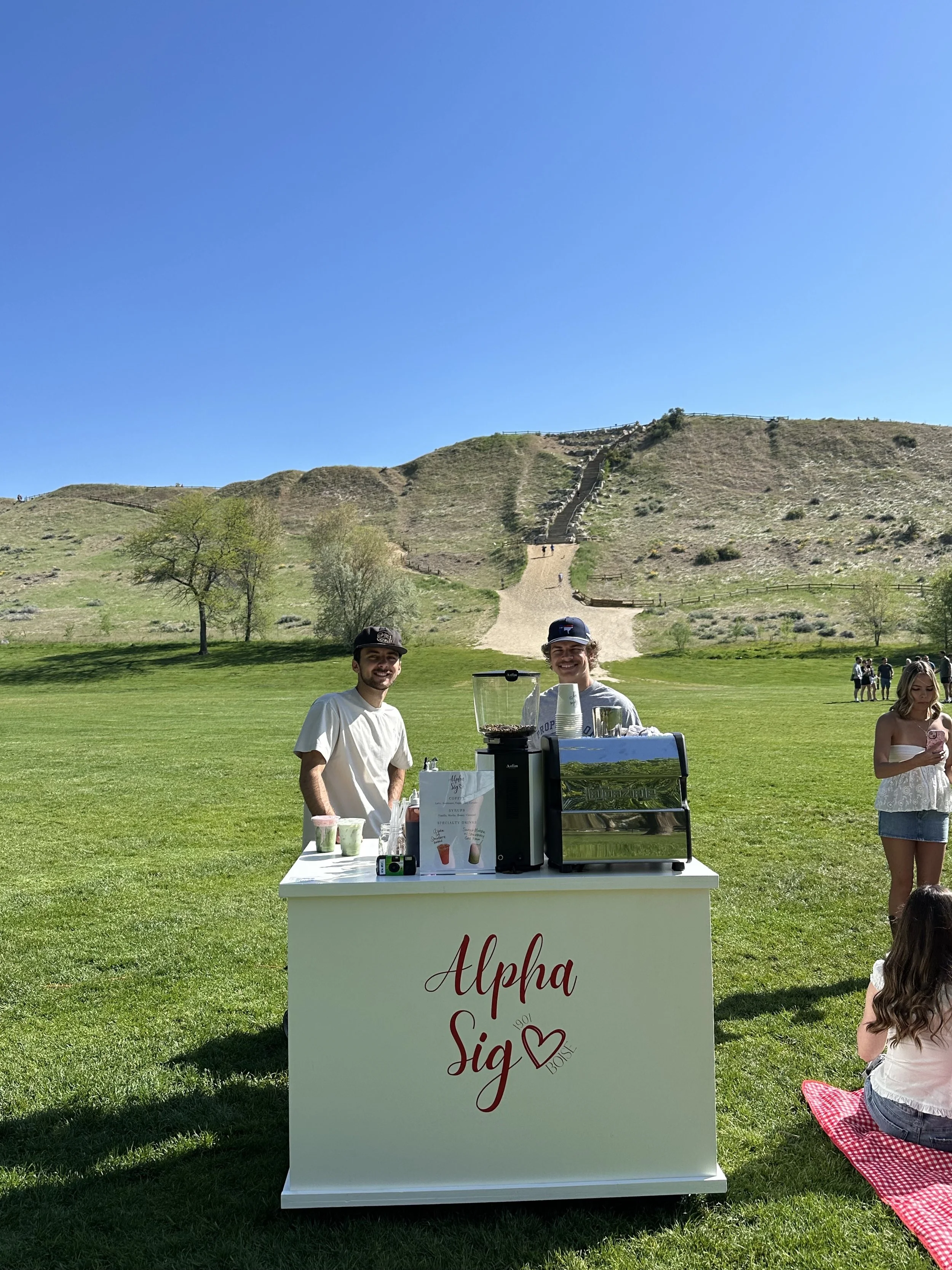 A coffee stand labeled 'Alpha Sig' Mobile Specialty Coffee Cart and Espresso Bar Catering Boise Idaho and the Treasure Valley