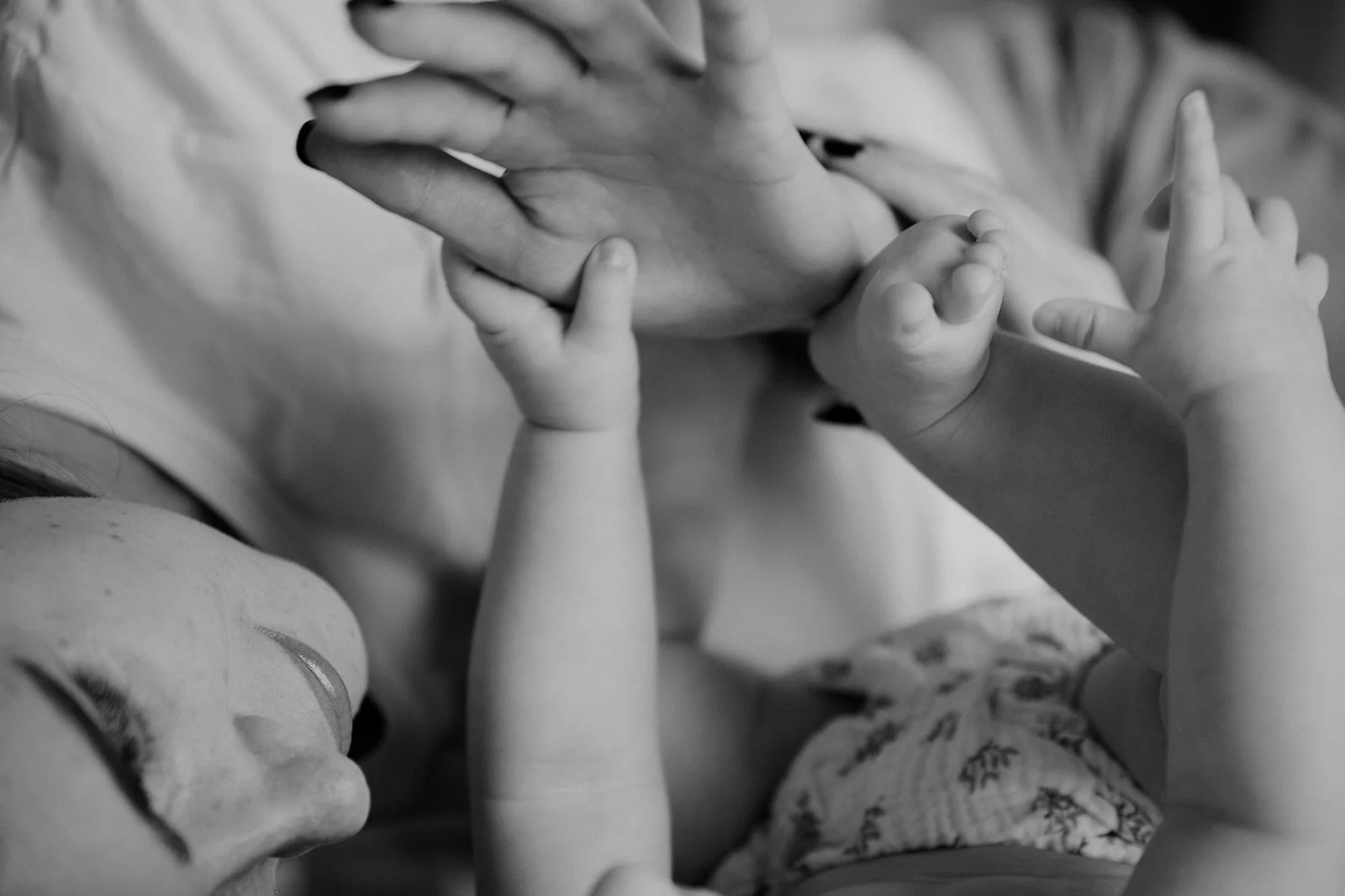 A woman and two children holding hands, with one adult and two babies, captured in black and white.