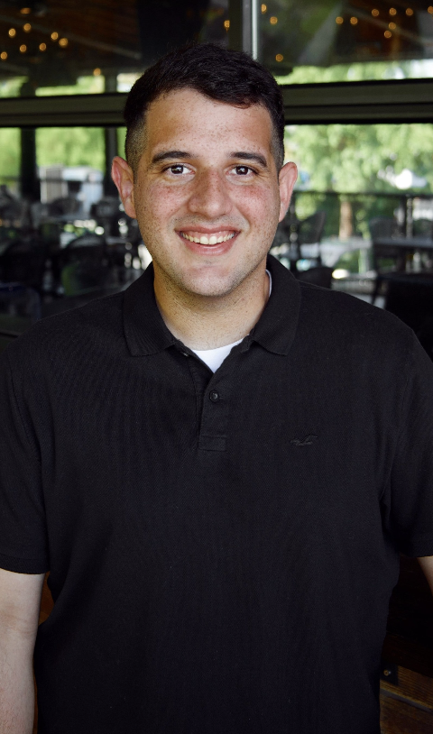 Man in a black polo shirt smiling indoors