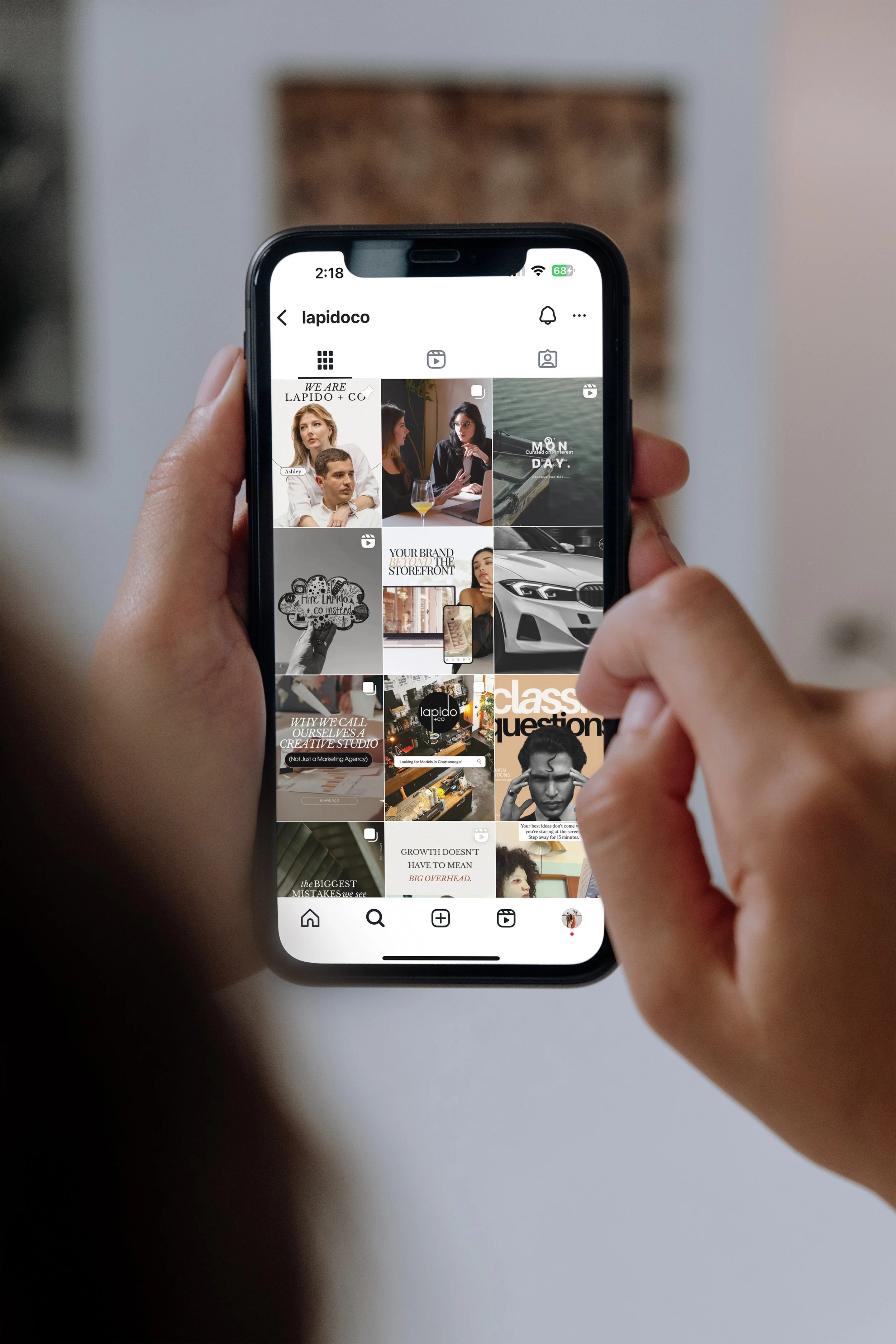 Person holding a smartphone displaying an Instagram profile with various posts and videos.