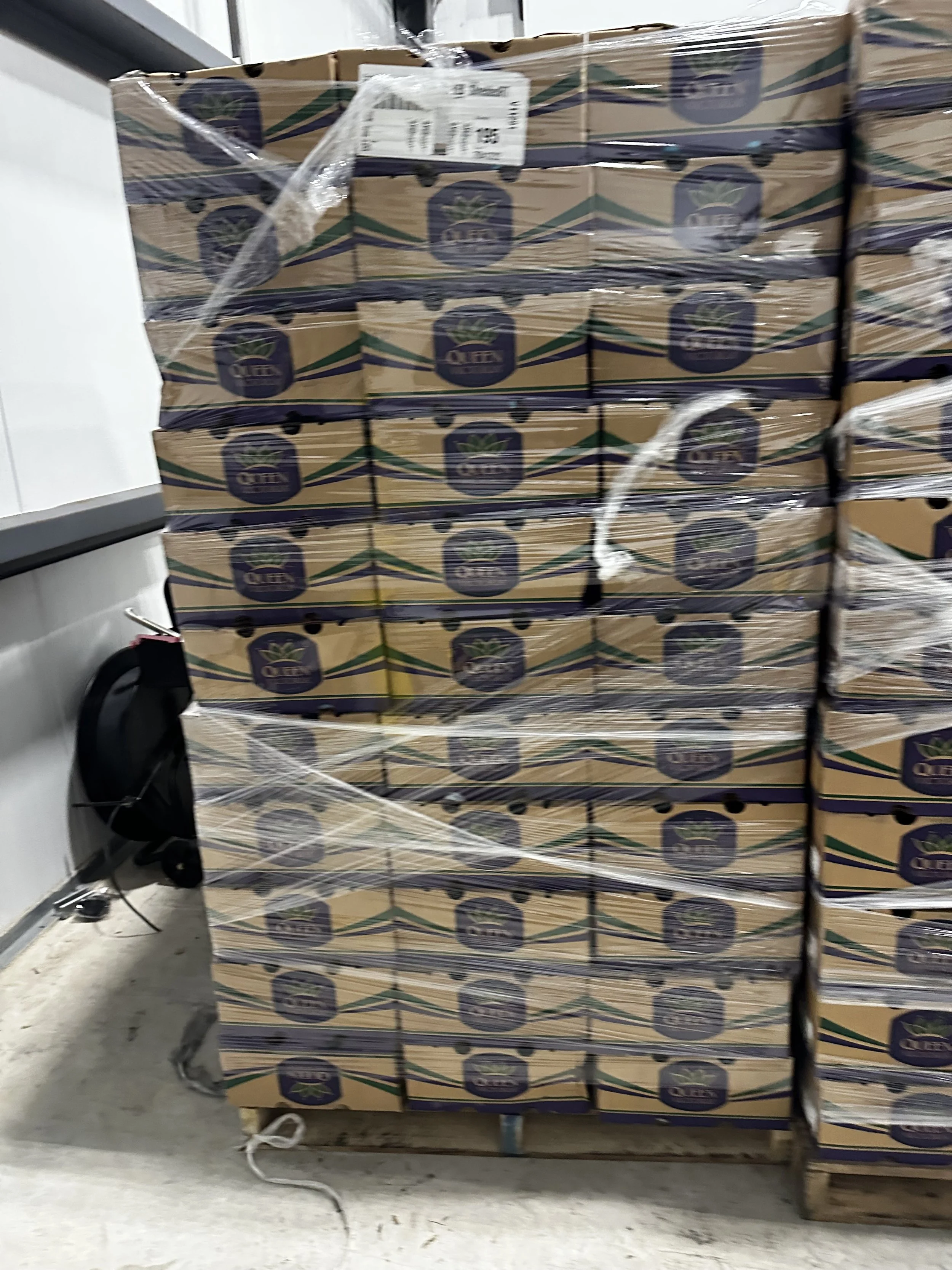 Stacked boxes wrapped in plastic and placed on a pallet in a warehouse.