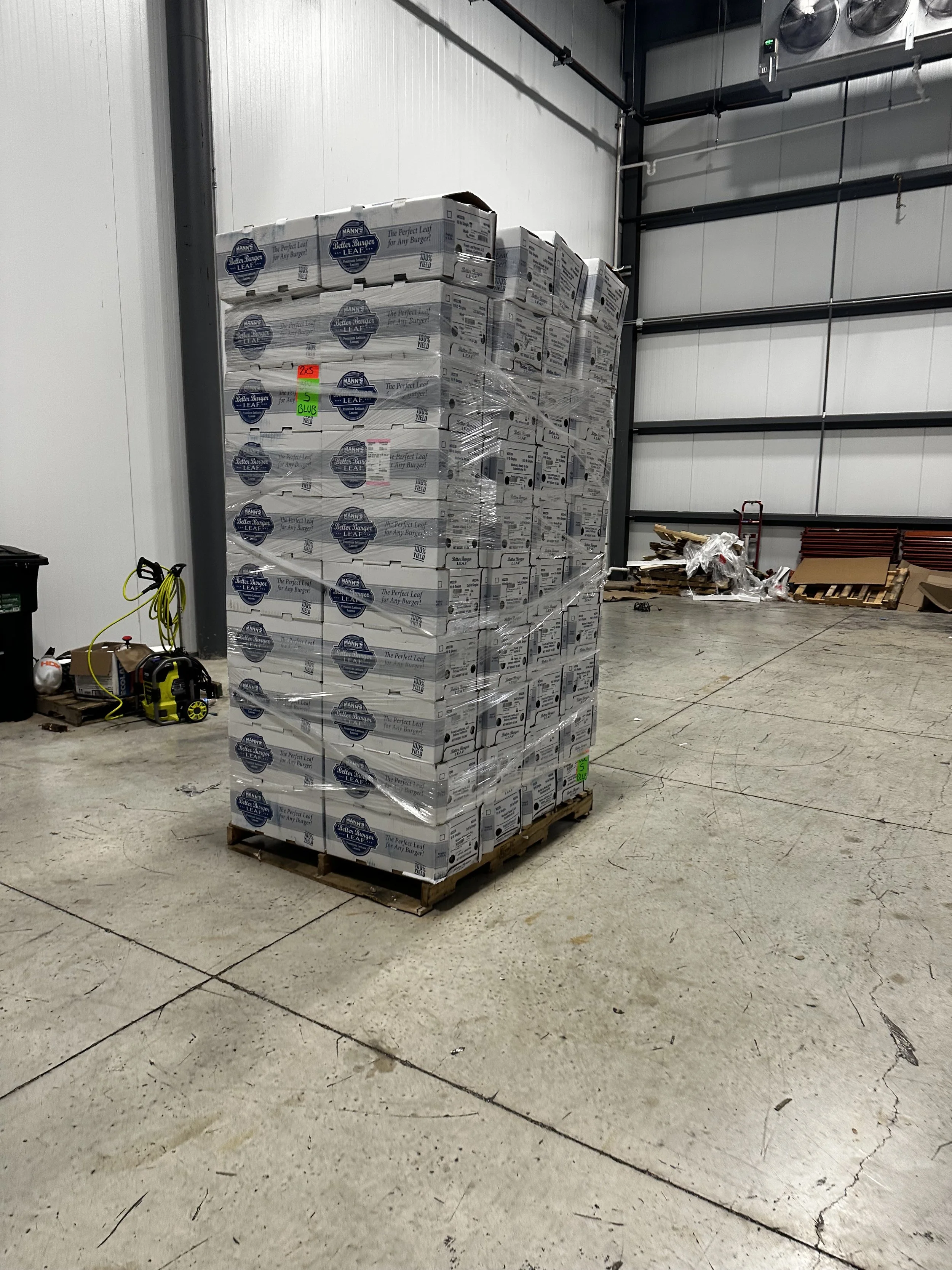 Pallet of canned Blue Runner Leaf burgers wrapped with plastic in an industrial warehouse.
