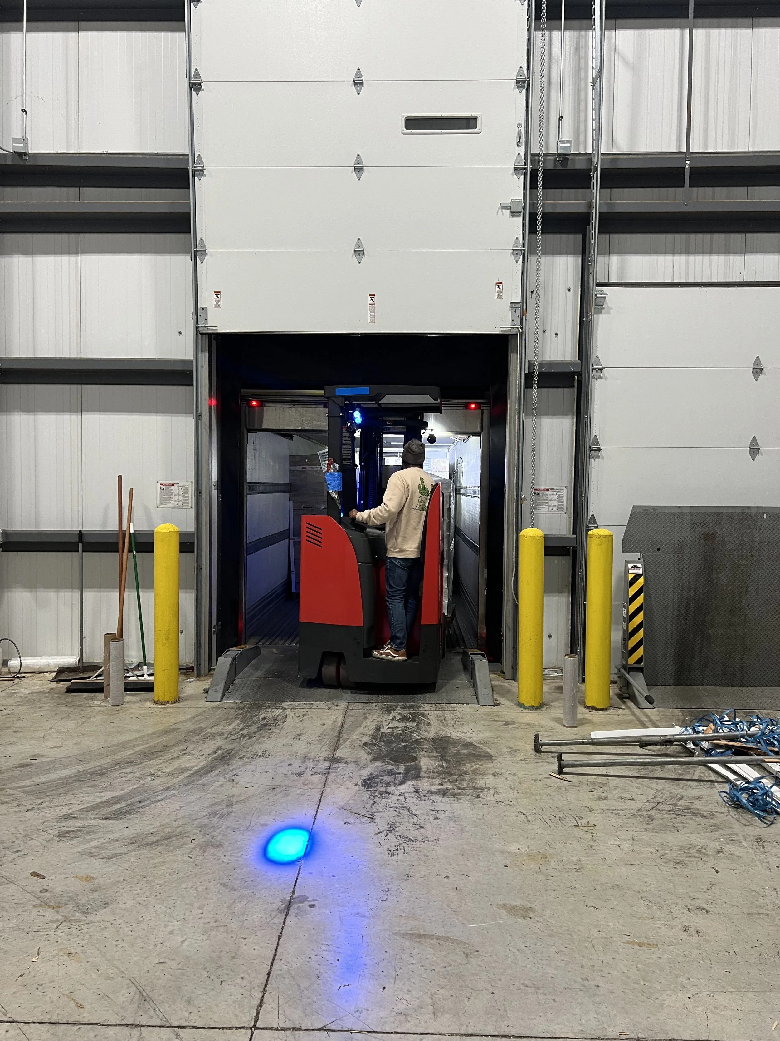 Person operating a forklift in a warehouse loading dock area.