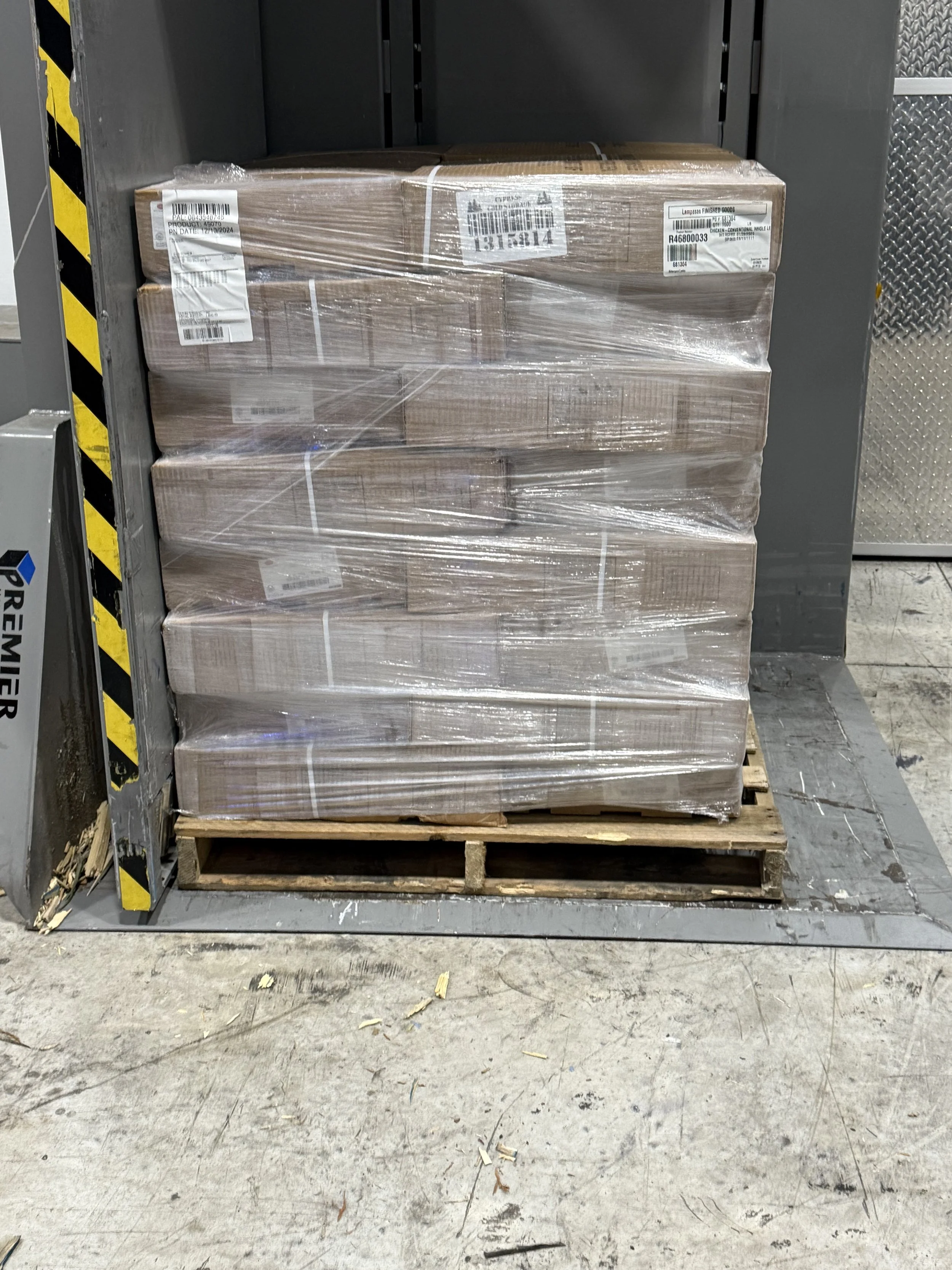 A pallet of boxed goods wrapped in plastic on the warehouse floor.