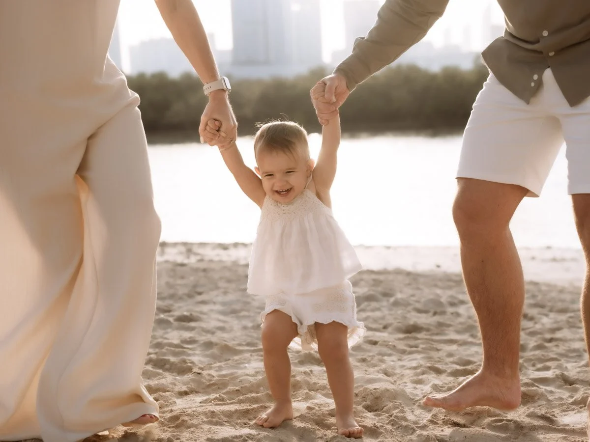 baby holding parents hands for photos in Reem Central Park