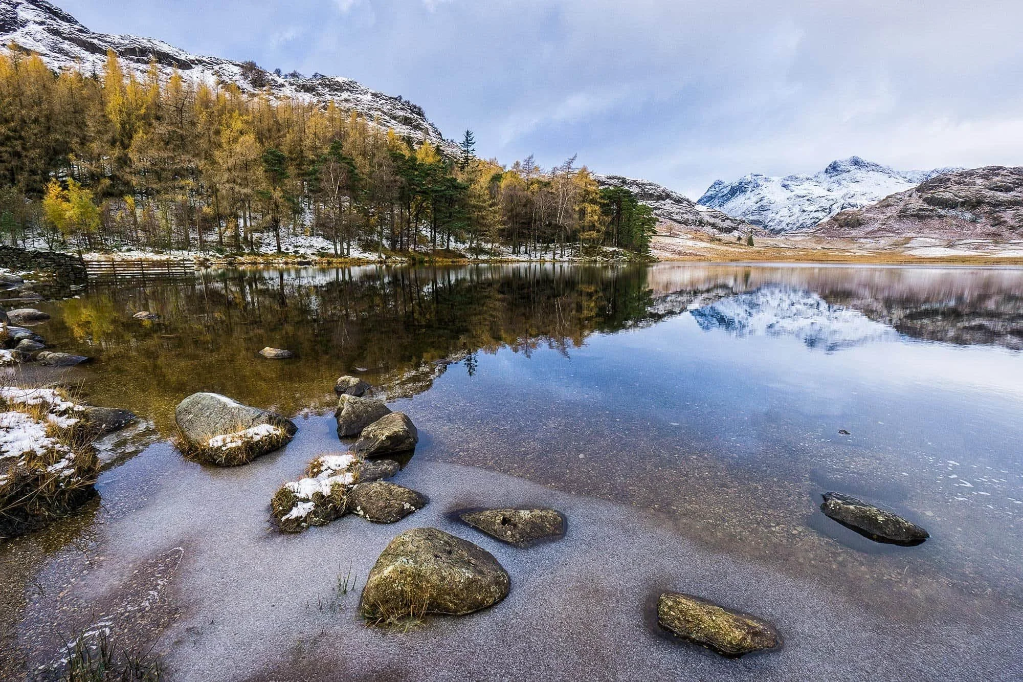 Snow-capped Langdale Pikes reflected in serene Blea Tarn.