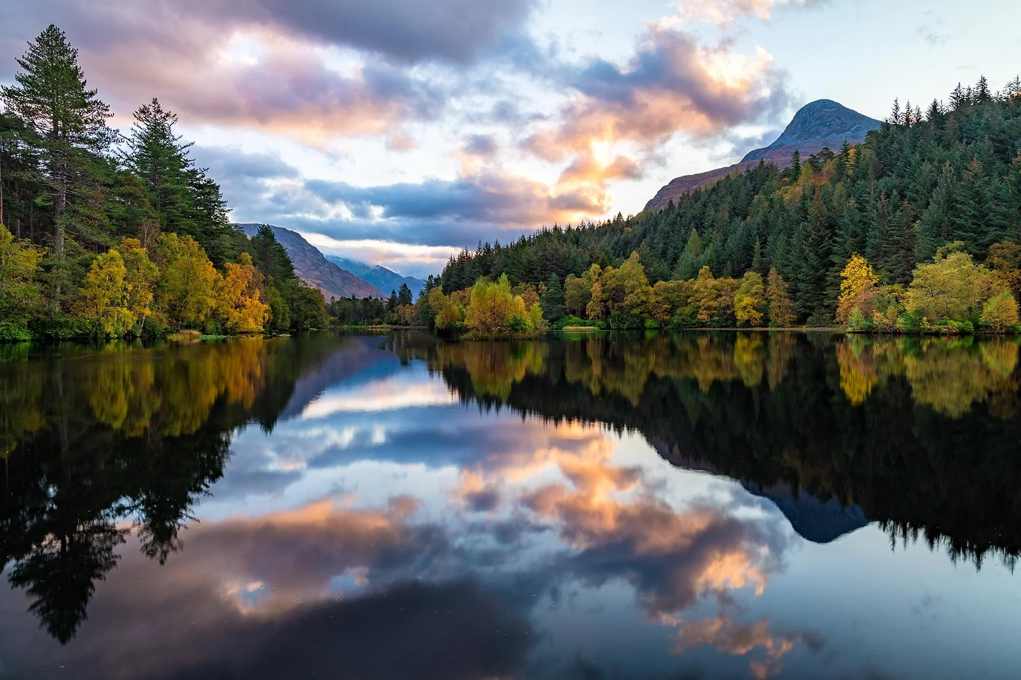 Beautiful autumn sunrise with stunning reflections of the Pap of Glencoe in Glencoe Lochan