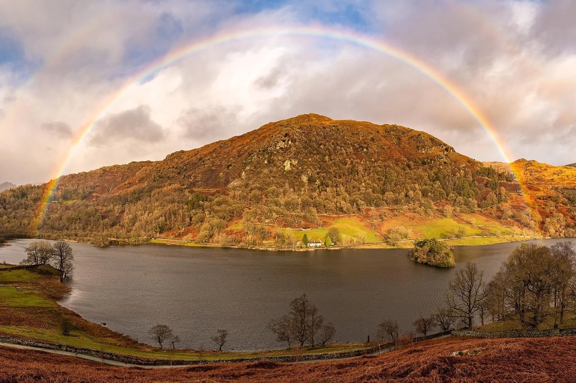 A rainbow arches over Rydal Water on a rainy day in Lakeland
