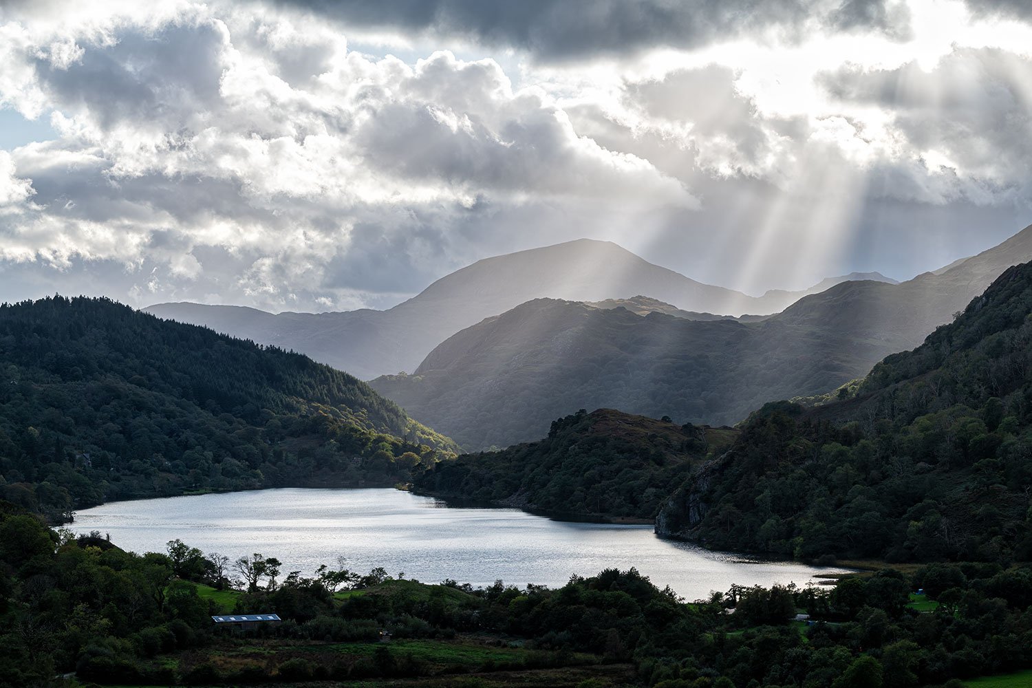 Sunburst breakthrough over the green autumn ridges of Nant Gwynant valley in Eryri (Snowdonia) National Park, North Wales.