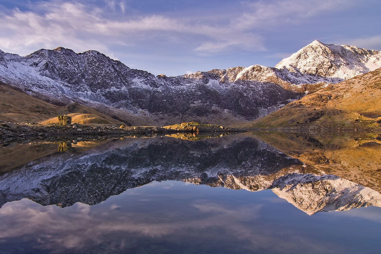 A Snowdonia view of Snow covered Snowdon mountain reflected in the lake of Llyn Llydaw on the Miners Track path.