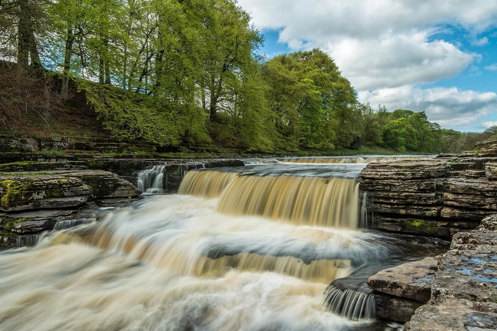 Fiery autumn foliage framing cascading Aysgarth Falls, North Yorkshire Dales.