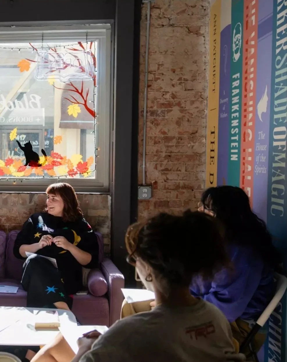 Photo of Caitlin sitting on couch talking about books with other book club members. Photo by Juliana Yamada for the Los Angeles Times
