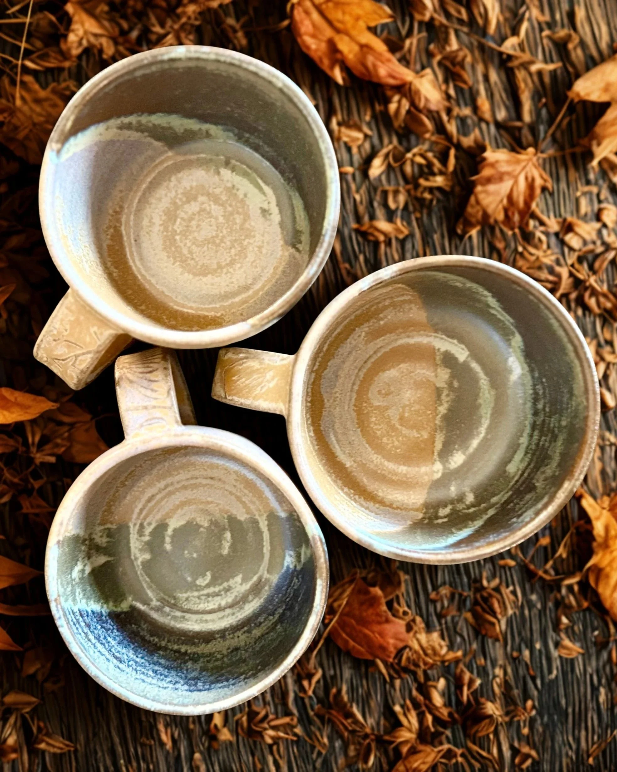 Hand-thrown ceramic mugs from the Tinamarie Clayworks Studio × Chapter Coffee collaboration, showing natural glaze variation
